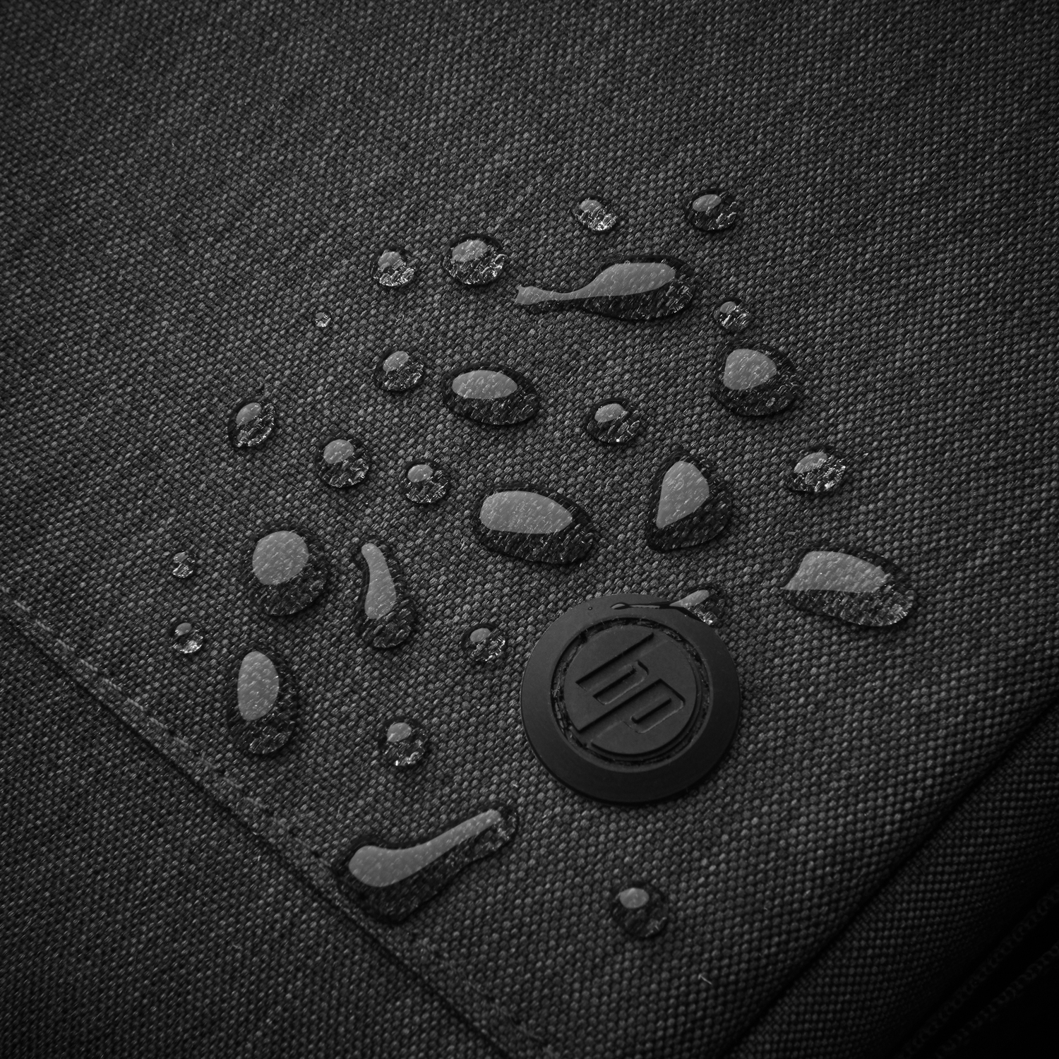 Close-up of black fabric with water droplets and an HP logo.
