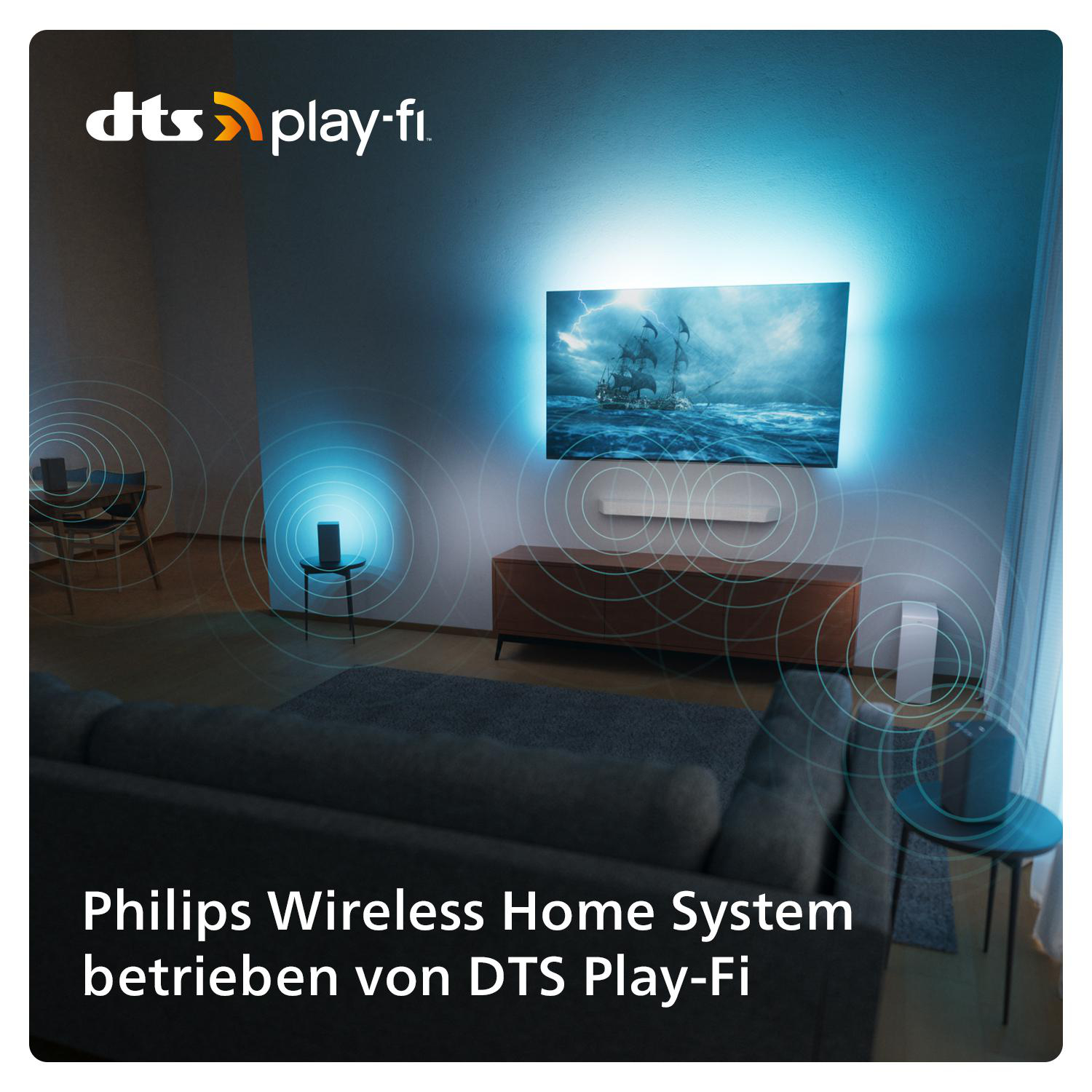 Wohnzimmer mit Fernseher an der Wand. Lautsprecher und Sofa sind sichtbar.