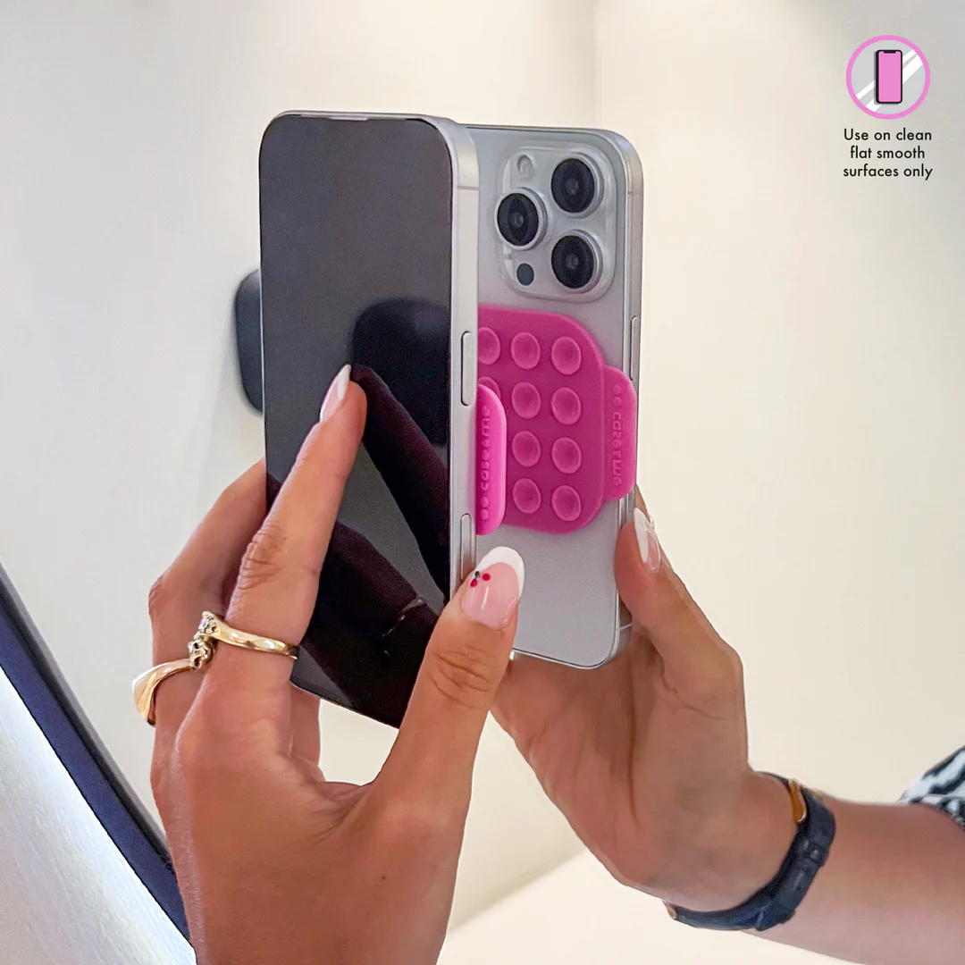 Hände halten ein silbernes Telefon mit einem angebrachten rosa Telefonhalter.