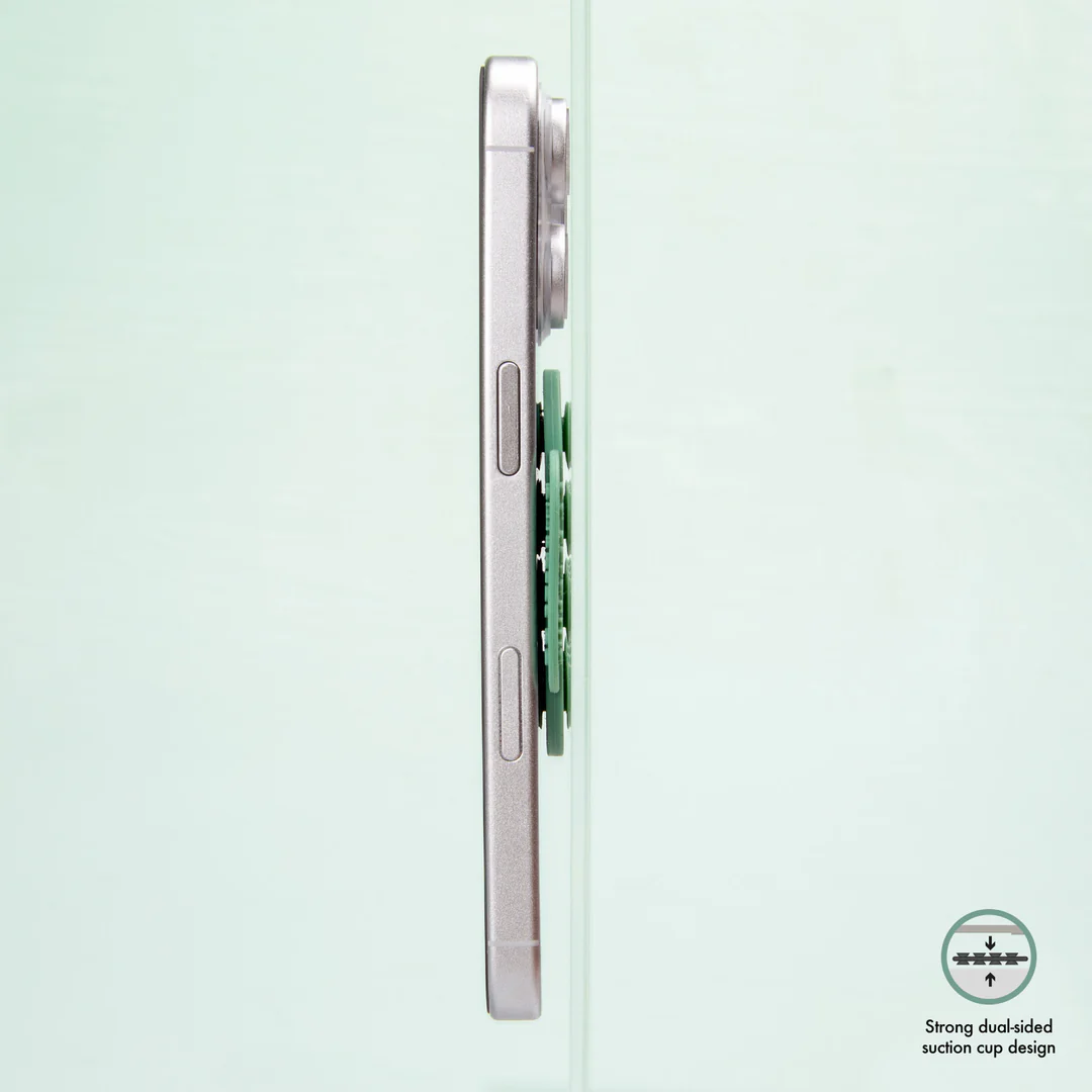 Ein Mobiltelefon, das an einem gr ünen Saugnapf befestigt ist, der an Glas befestigt ist.
