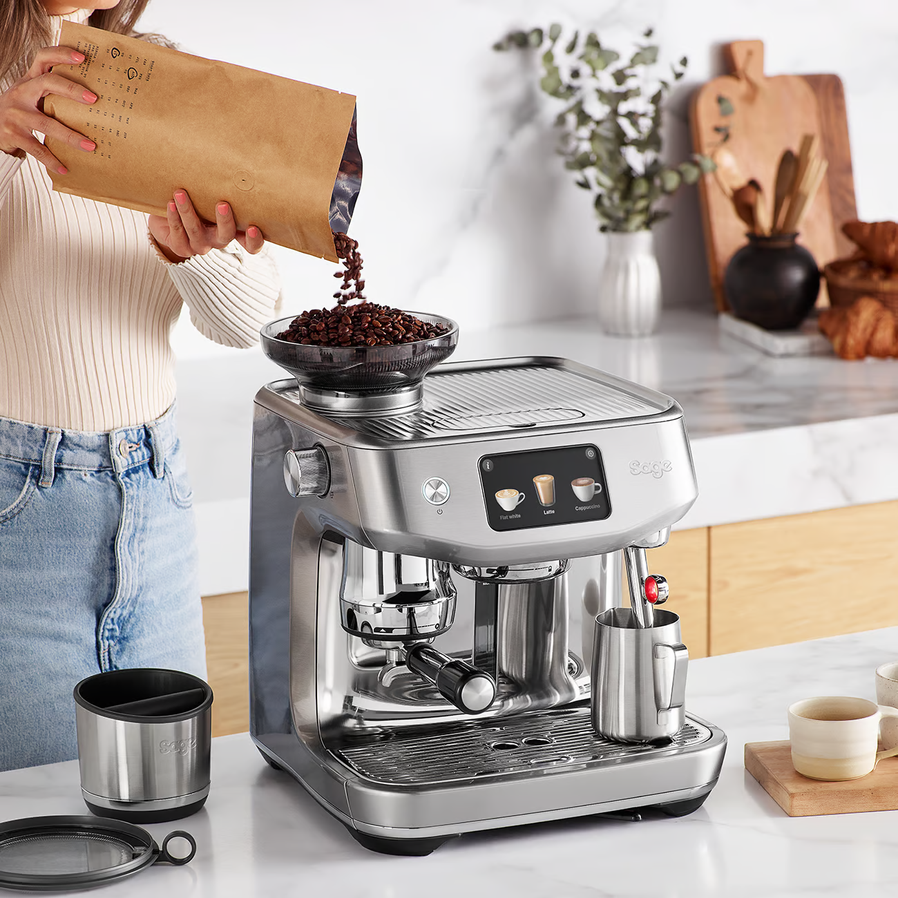 Una persona versa chicchi di caffè in una macchina da caffè con accessori.