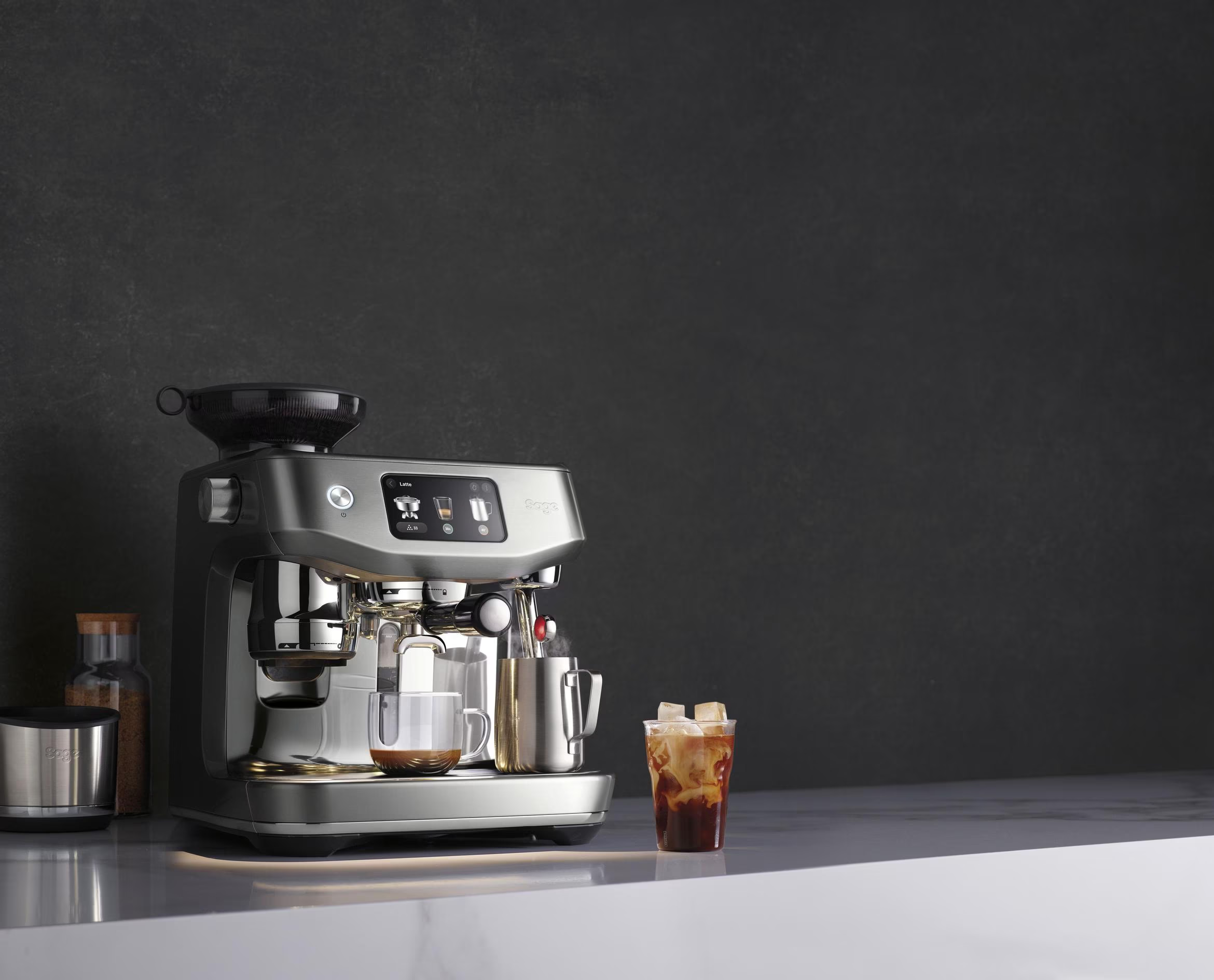 Una macchina per il caffè con una tazza di caffè, ghiaccio e un piccolo contenitore accanto.