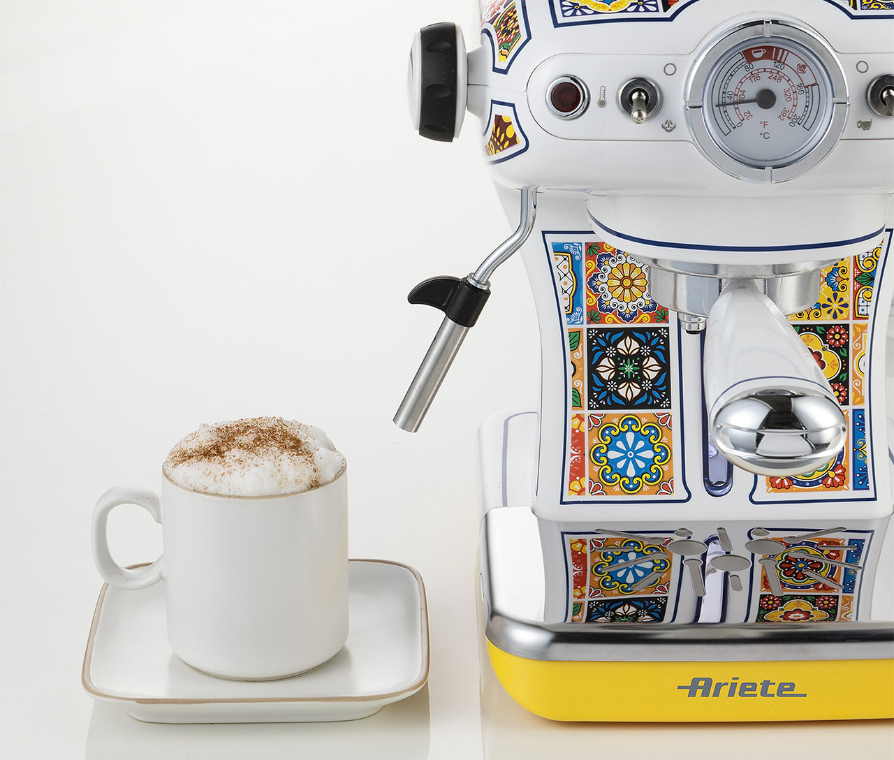 Macchina per caffè espresso bianca con motivi colorati. Tazza di cappuccino su un piattino bianco. Base gialla.