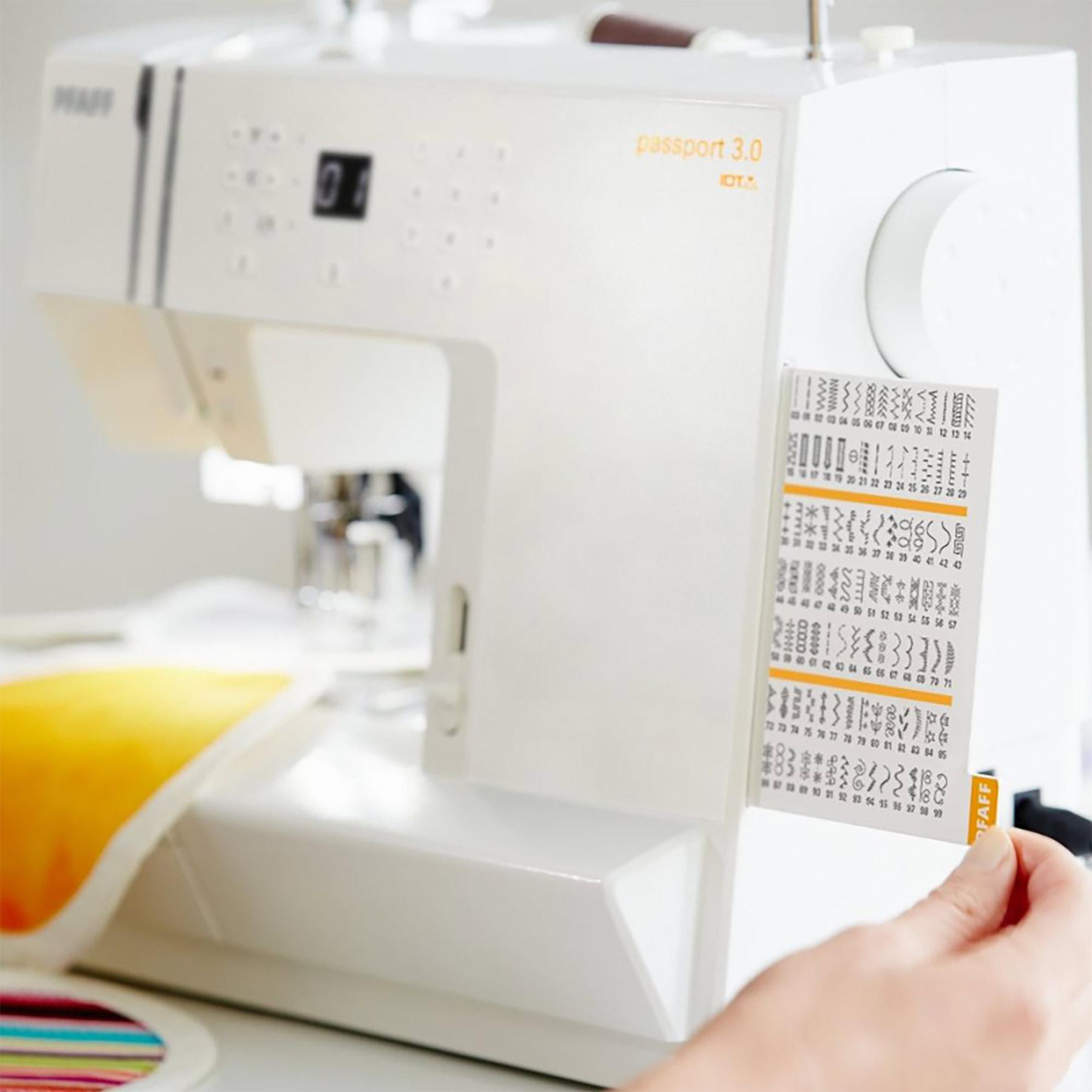 Weiße Nähmaschine mit Stichmusterkarte, Hand hält Karte, gelber Stoff.