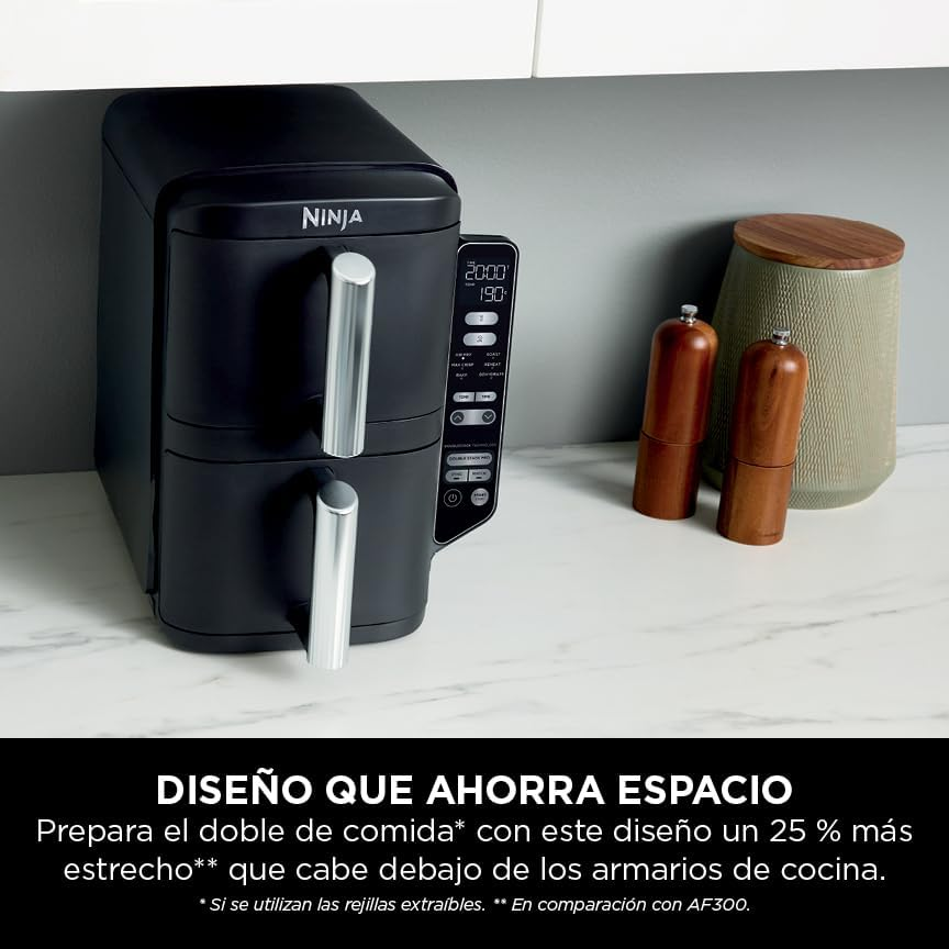 Una freidora de aire negra con asas plateadas y un panel de control. Al lado, saleros y pimenteros de madera.