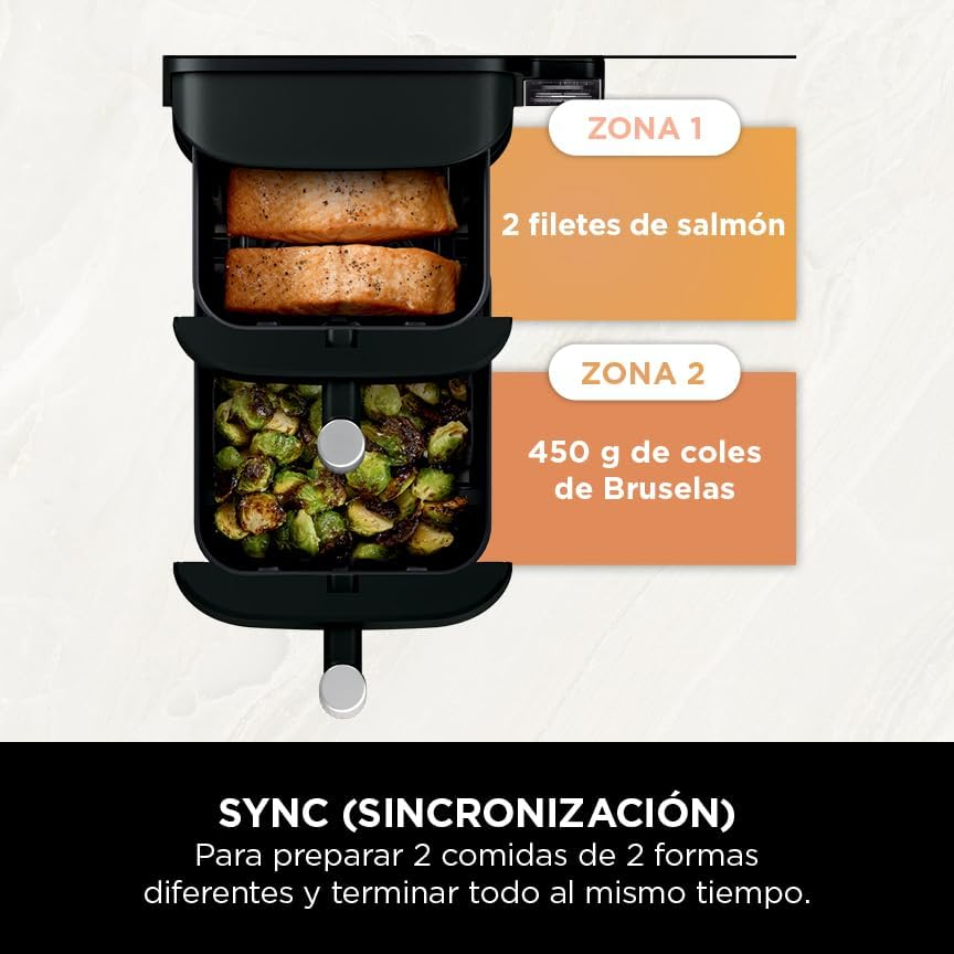 Una freidora de aire con dos cestas que contienen filetes de salmón y coles de Bruselas. Texto en español.
