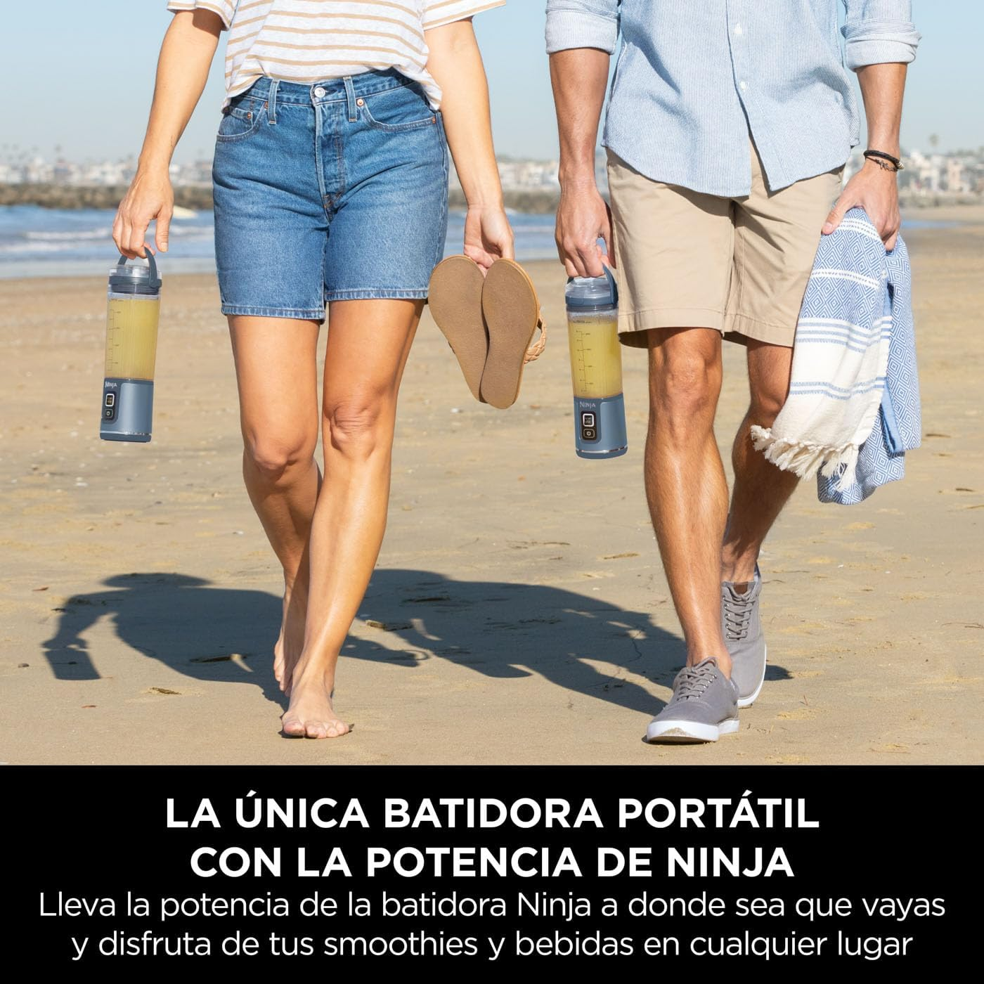 Dos personas caminando en la playa, sosteniendo batidoras portátiles. Superposición de texto en español.