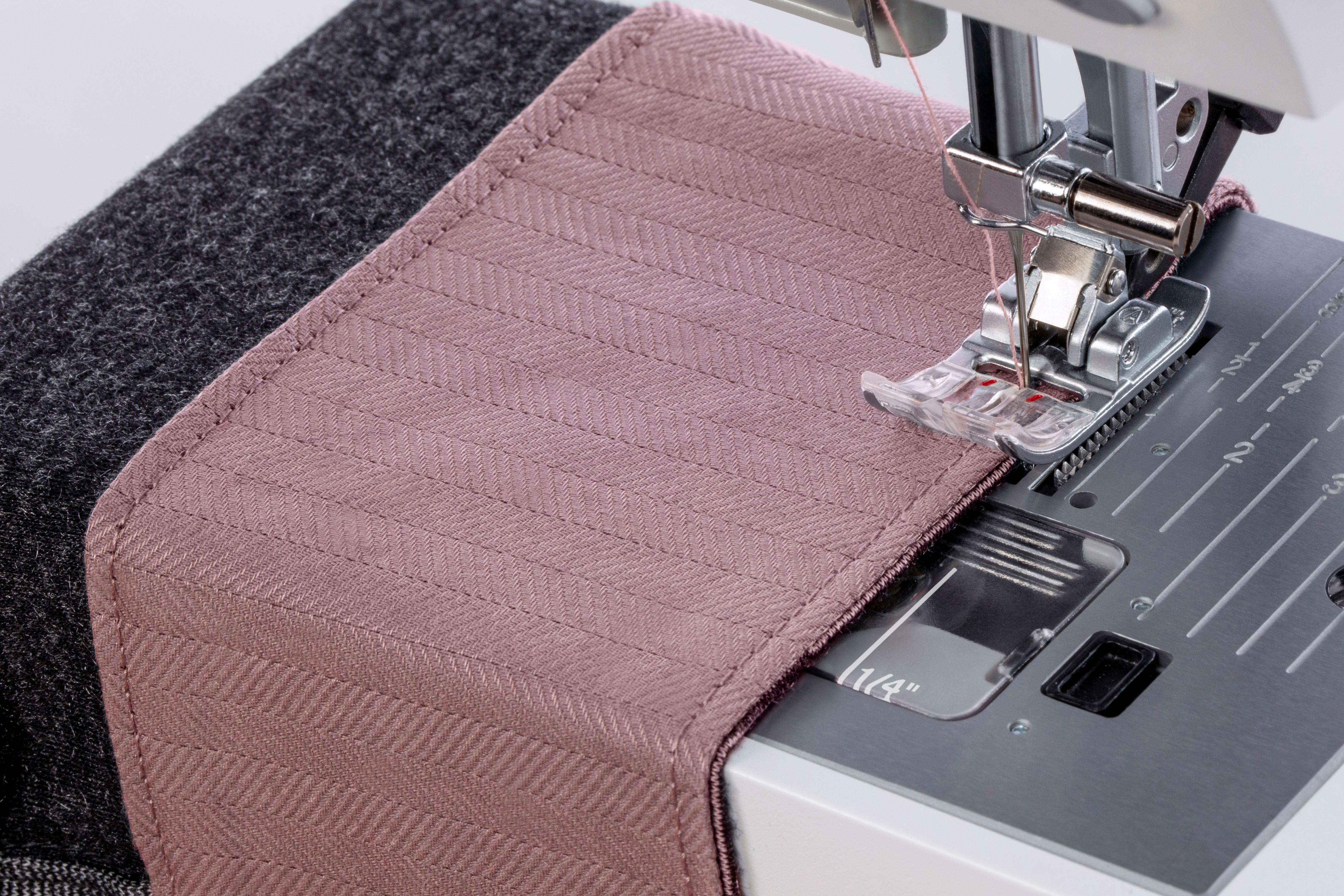 Nähmaschine näht rosa Stoff mit geometrischem Muster, Nahaufnahme.