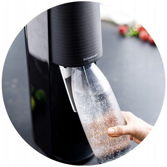 Osoba wlewa wodę do saturatora. Widoczny SodaStream Terra.