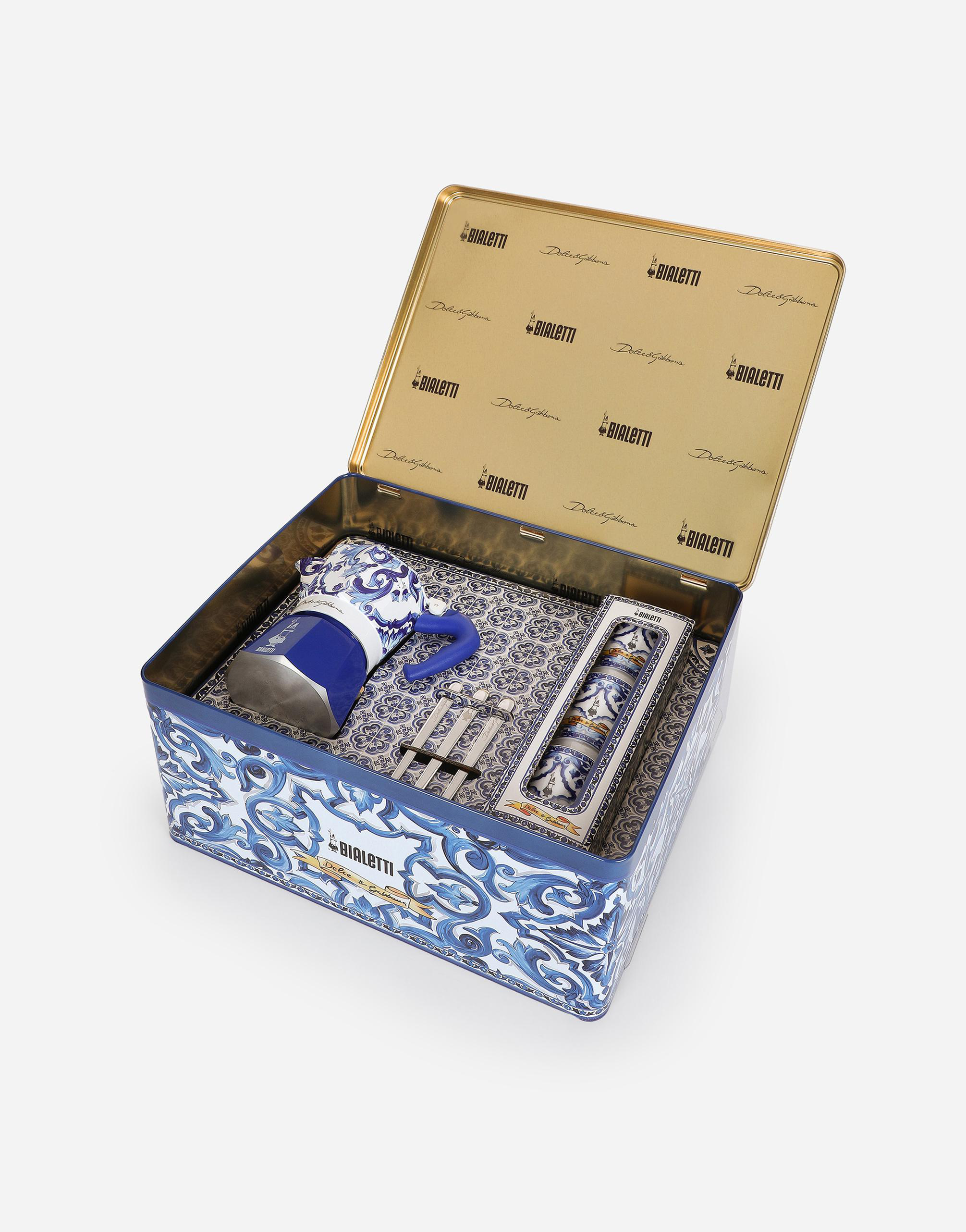 Ein dekoratives blau-weißes Kaffeeset wird in einer Metalldose mit goldenem Deckel gezeigt.