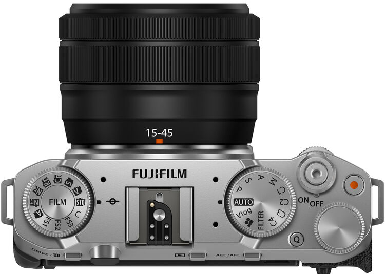Felülnézet egy ezüst Fujifilm fényképezőgépről, fekete objektívvel és különböző tárcsákkal és gombokkal.