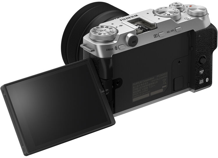 Ezüst-fekete Fujifilm kamera, nyitott képernyővel, objektívvel.