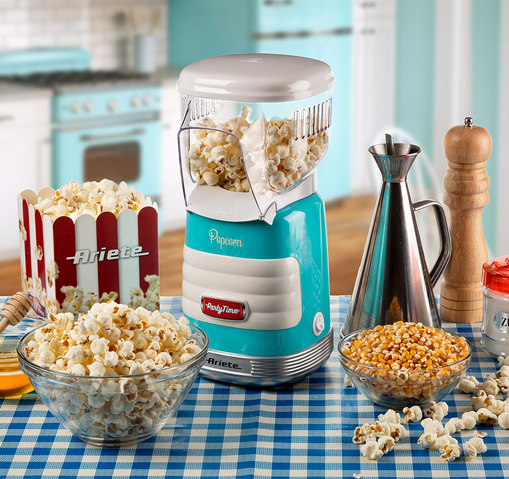 Macchina per popcorn con popcorn in una ciotola e un contenitore. Una cucina blu e bianca è visibile.