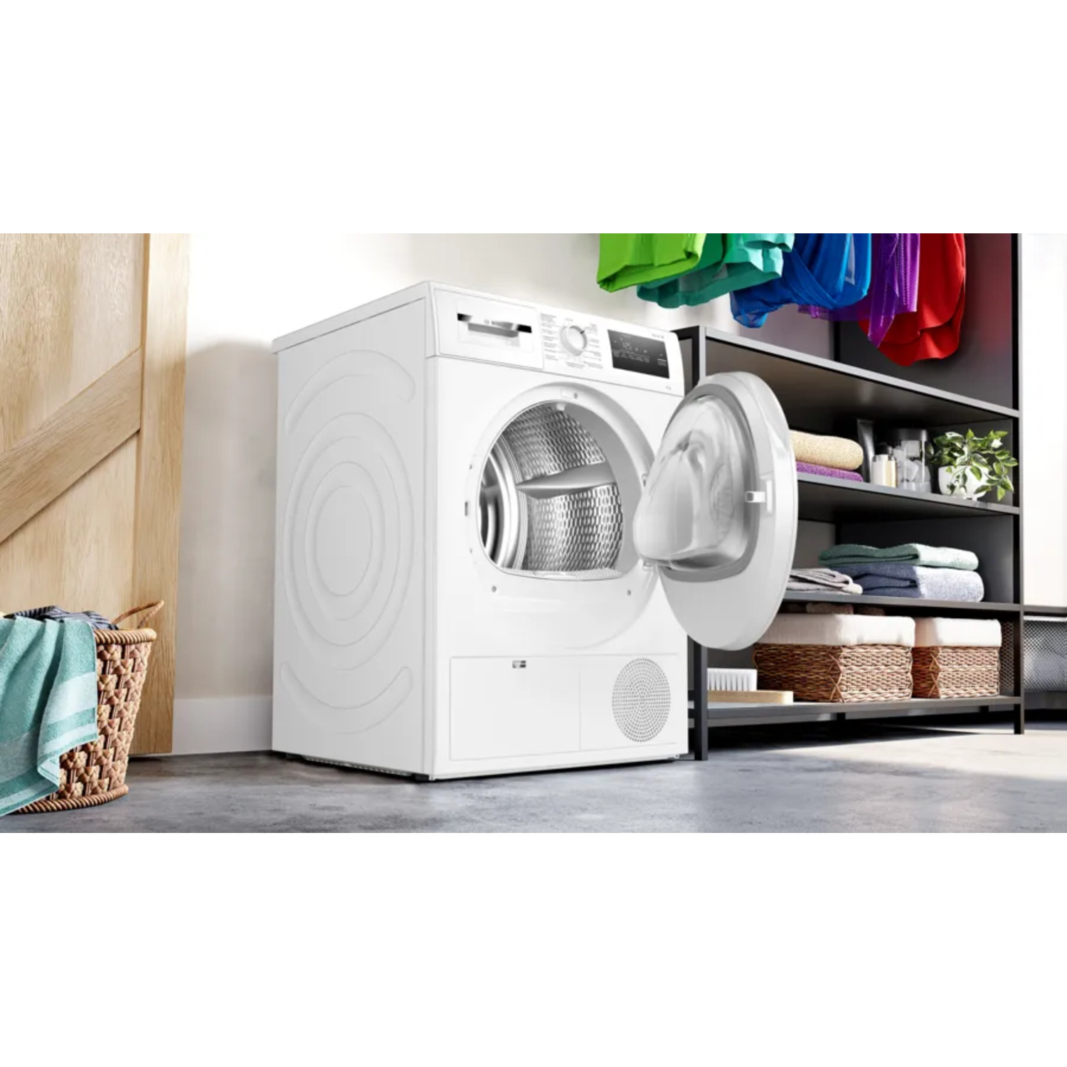 A white dryer with an open door, laundry items and a wooden door in the background.