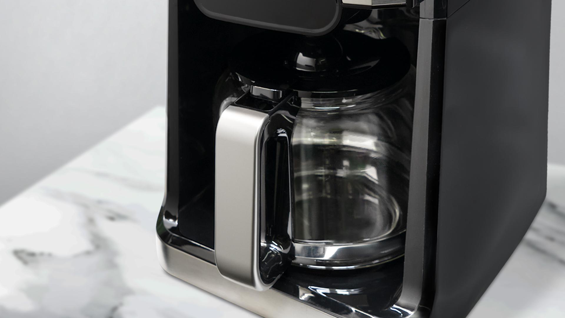 Nahaufnahme eines schwarzen Kaffeeautomaten mit Glaskaraffe und silbernen Akzenten.
