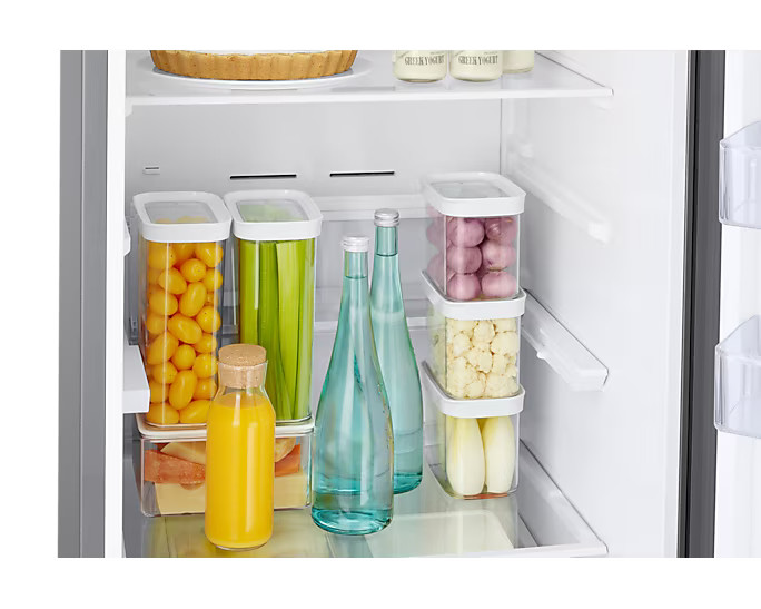 Wnętrze lodówki z pojemnikami na żywność i butelkami. Dobrze zorganizowane i czyste.