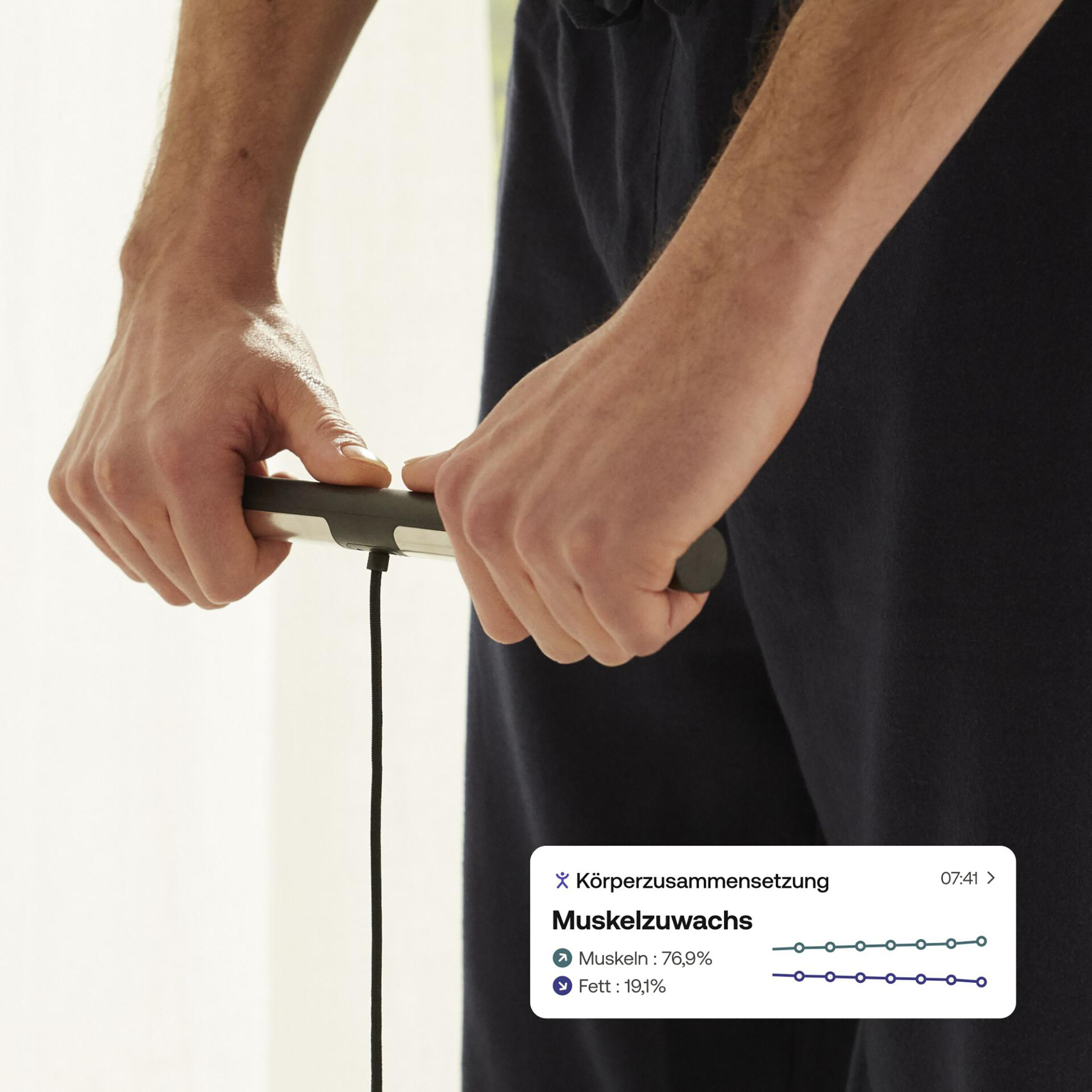 Eine Person hält eine Körperanalysewaage. Bildschirm zeigt Körperfett- und Muskelwerte.