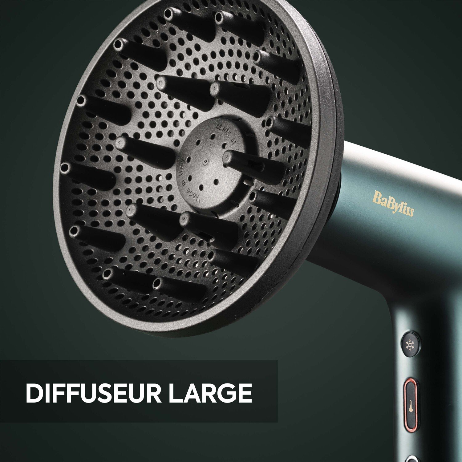 Un diffuseur noir pour un sèche-cheveux. Le diffuseur est grand et comporte de nombreux trous. Un sèche-cheveux Babyliss en arrière-plan.