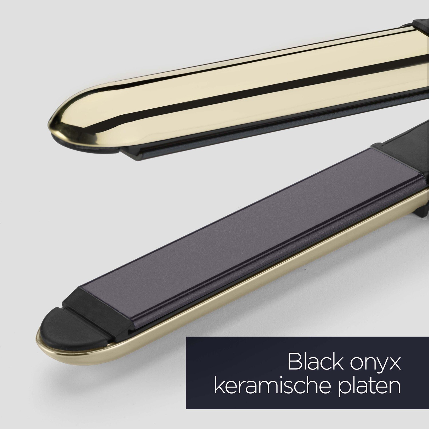 Close-up of a gold and black hair straightener with ceramic plates.