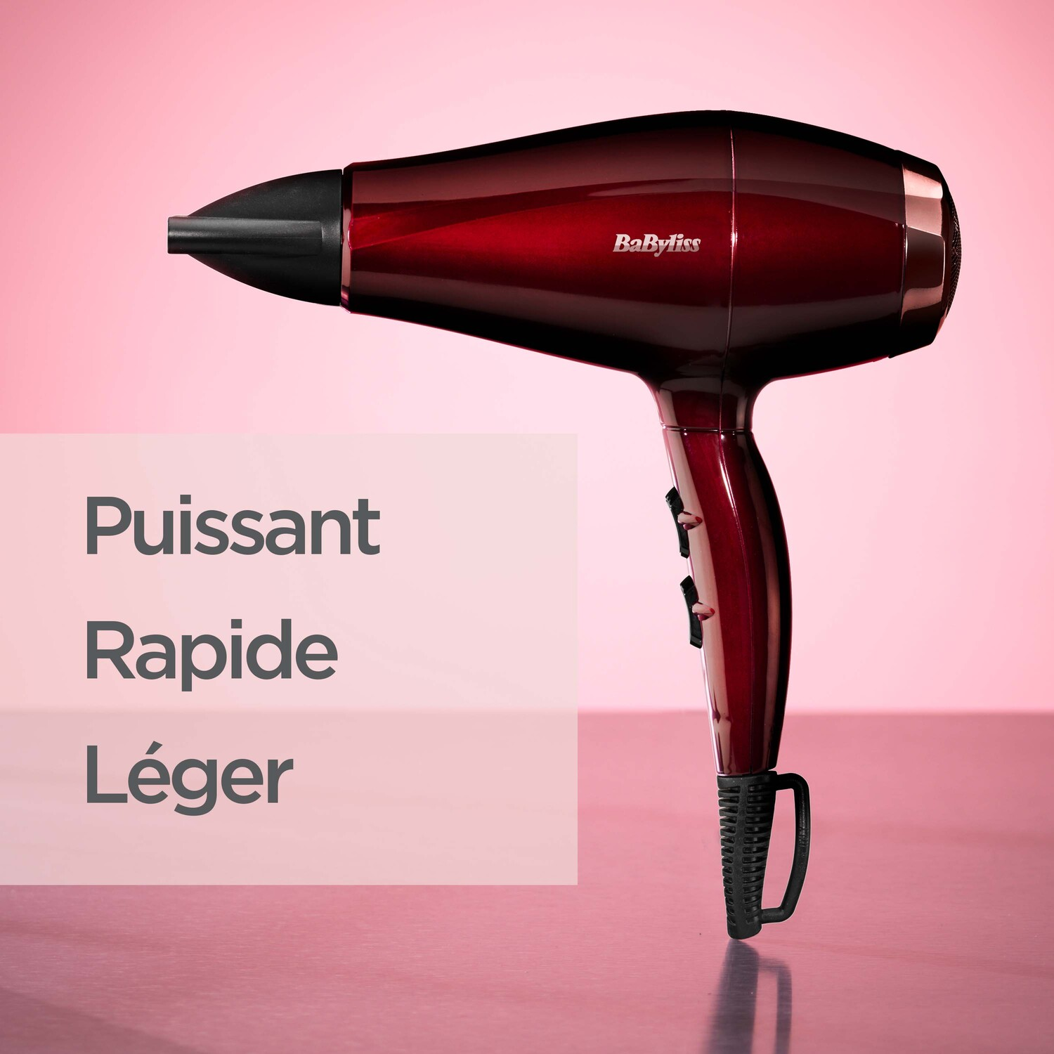 Sèche-cheveux rouge avec buse noire, poignée et boutons de commande.