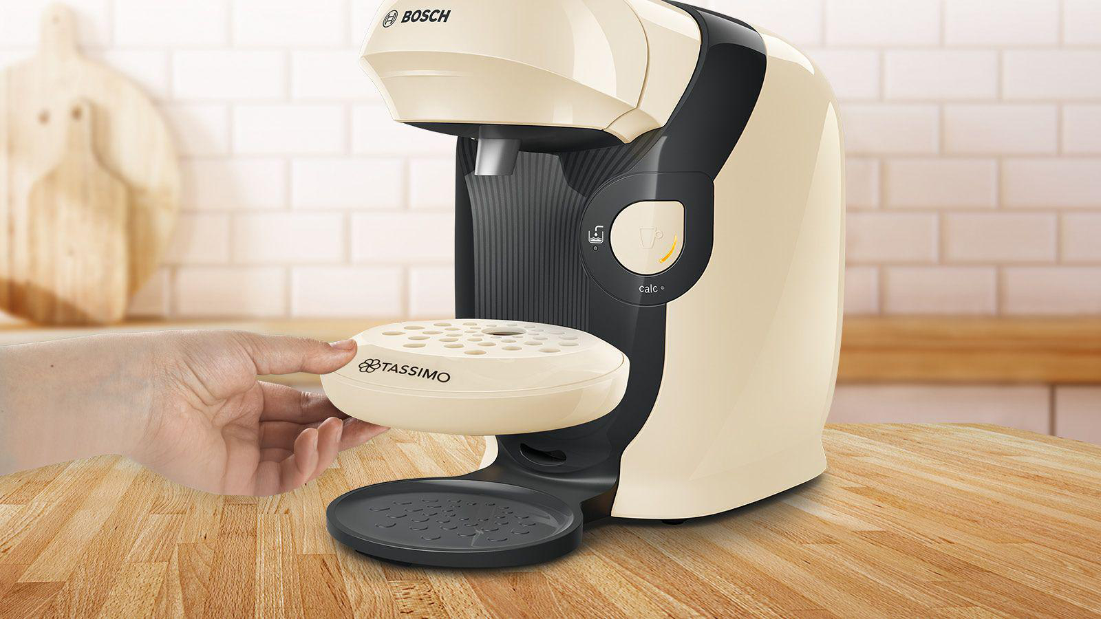 Cremefarbene Tassimo-Kaffeemaschine, Hand hält den Scheibenhalter.
