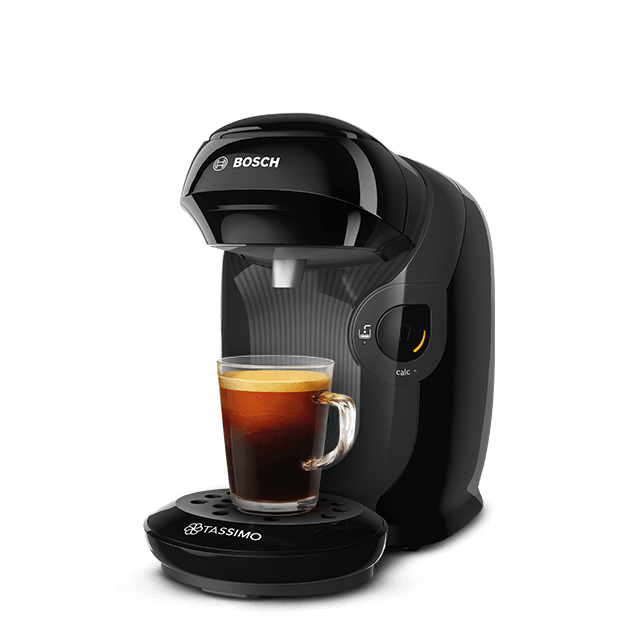 Schwarze Tassimo-Kaffeemaschine mit einer Tasse Kaffee. Die Maschine steht auf einem schwarzen Sockel.