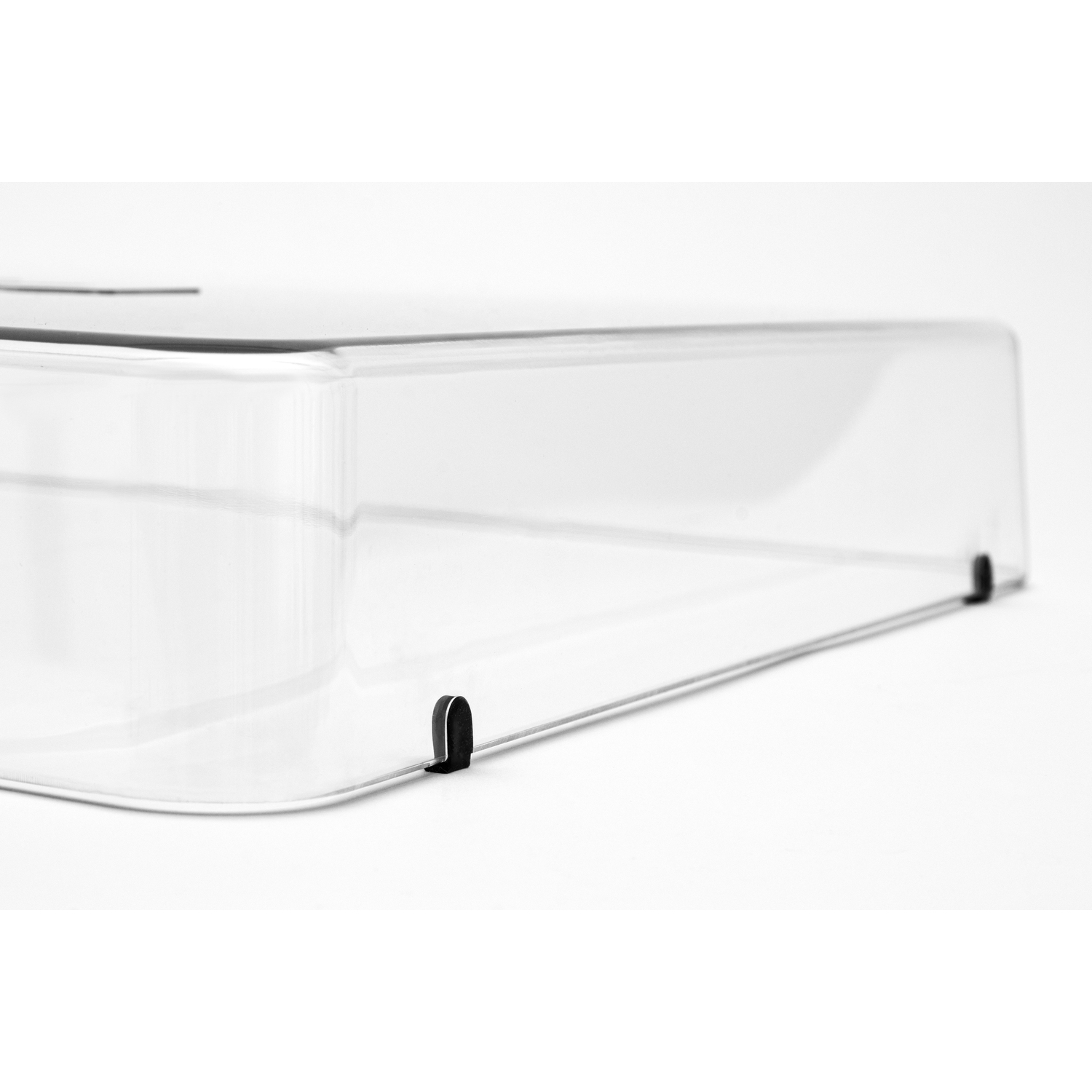 Un couvercle en plastique transparent, avec des clips noirs, sur une surface blanche.