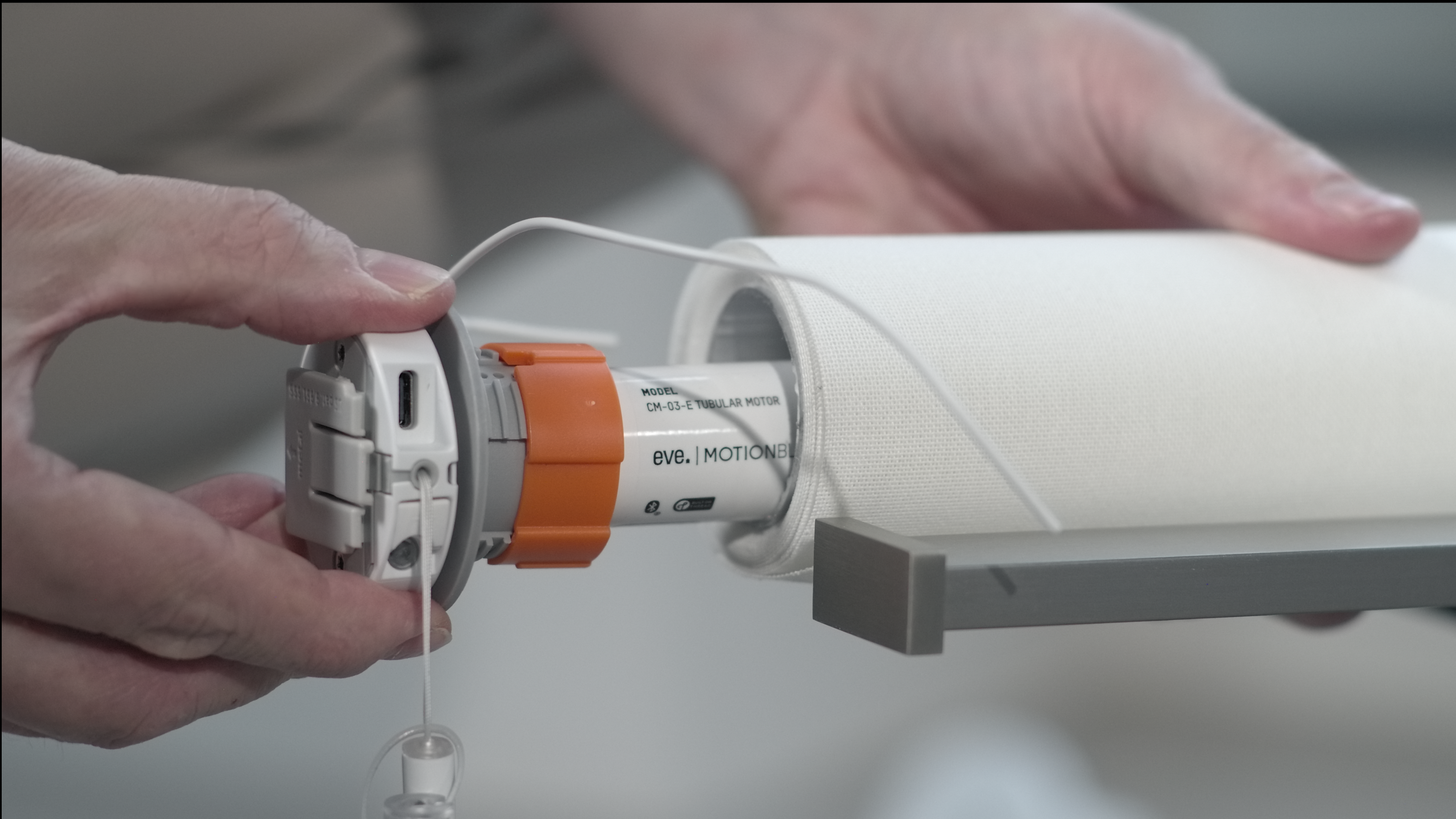 Hände installieren einen Rollladenmotor in ein weißes Rollladenrohr.