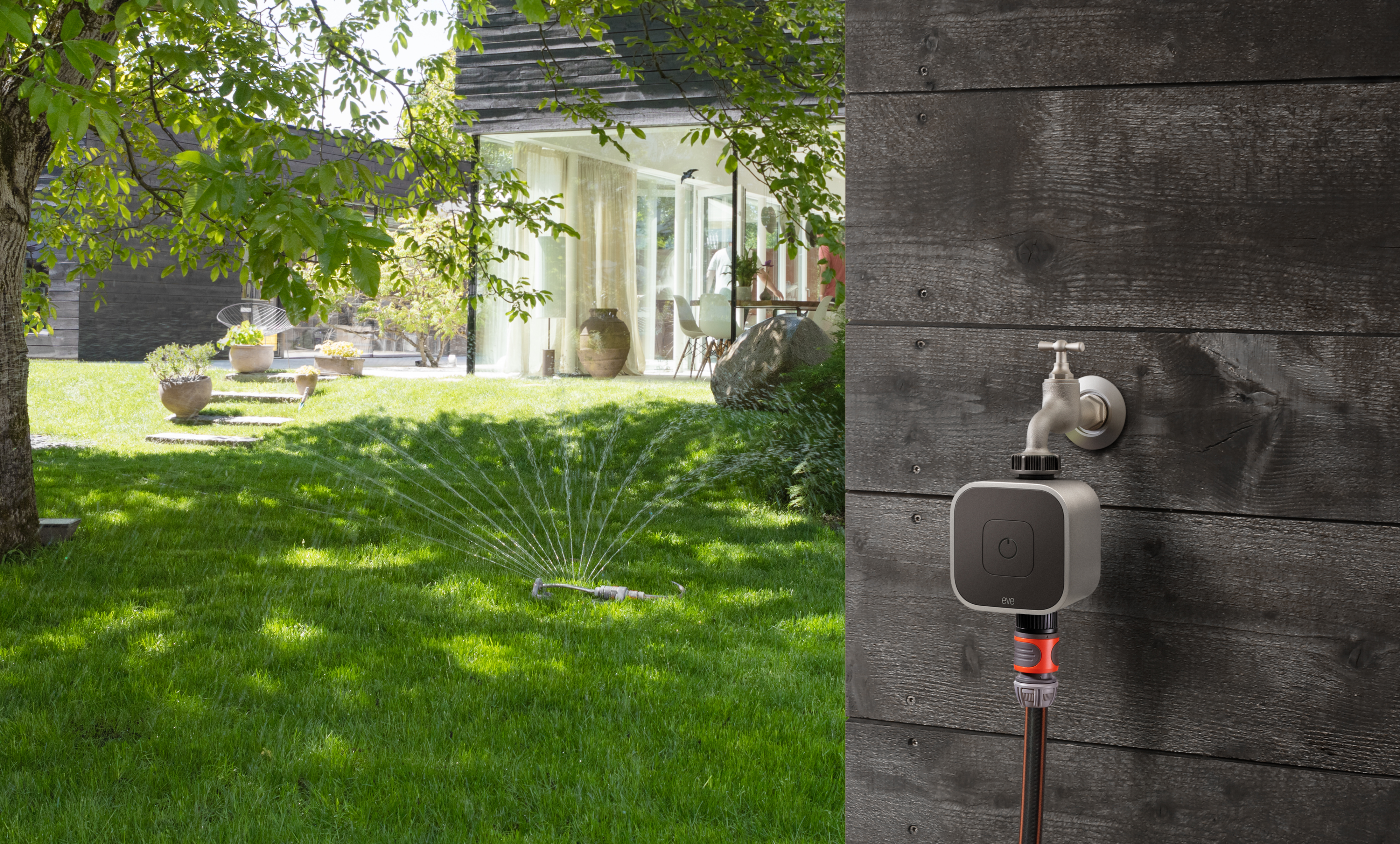 Rasen-Sprinkler in Betrieb, Wassersprühen und ein Wasserhahn mit Steuereinheit.