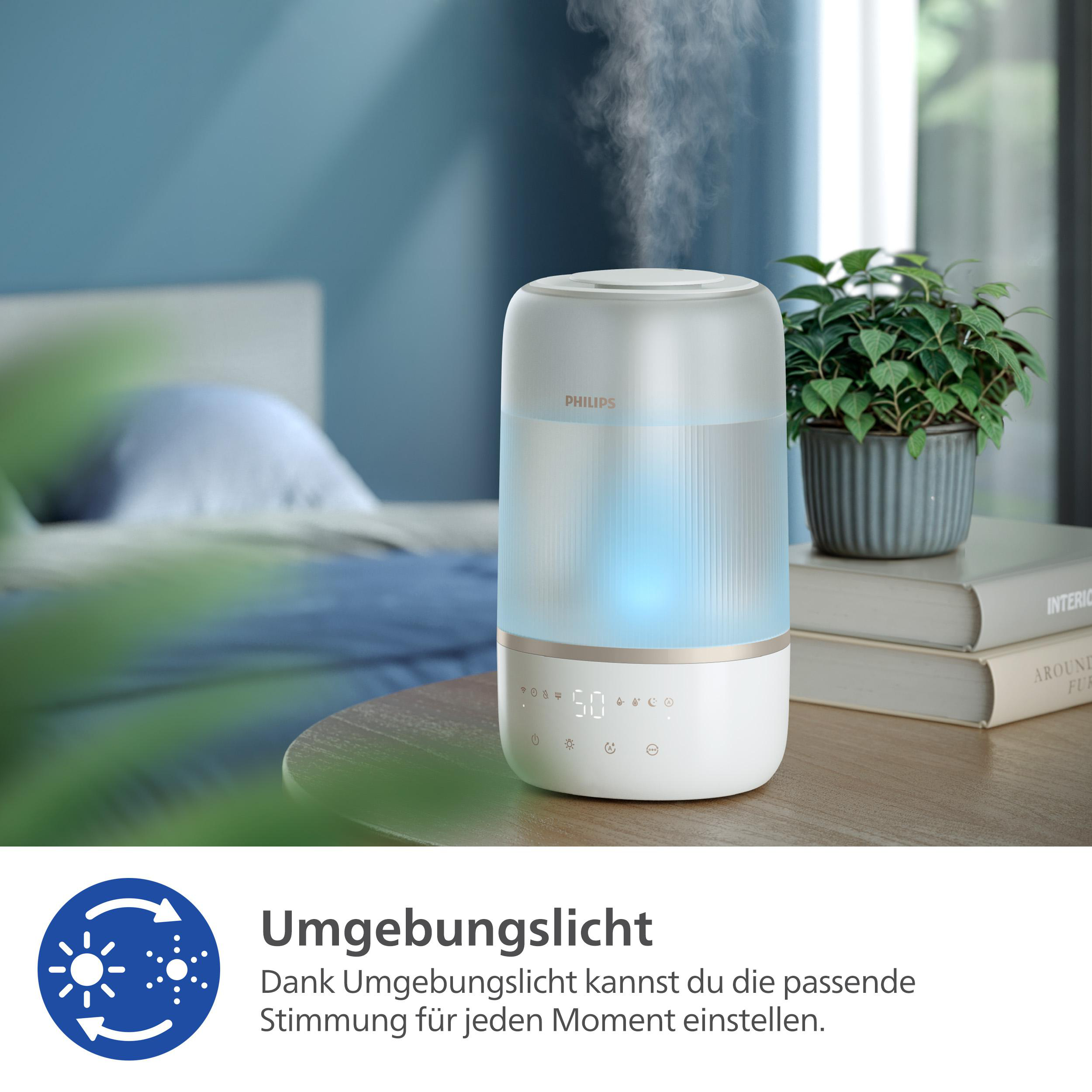 Weißer und klarer Luftbefeuchter auf einem Tisch. Dampf wird abgegeben. Pflanze im Hintergrund. Blaues Umgebungslicht.
