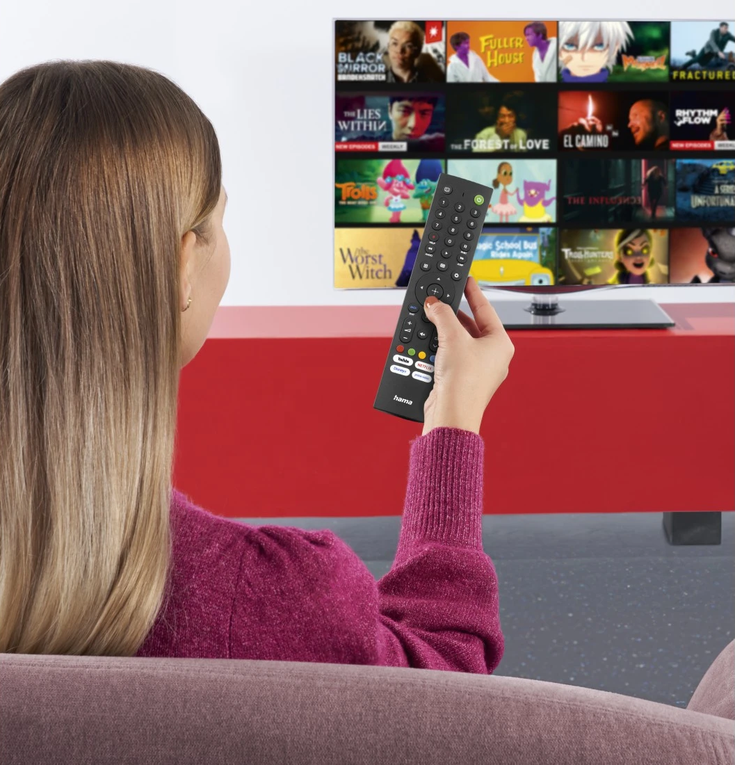 Nő tévét néz, távirányítót tart. A képernyőn filmborítók láthatók.