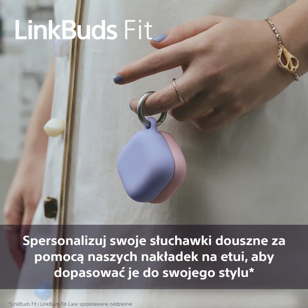 Ręka trzyma fioletowo-różowe etui na słuchawki. Osoba nosi bransoletkę i pierścionki. Lakier do paznokci jest jasnofioletowy.