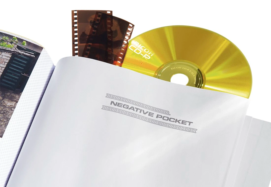 Nyitott könyv negatív zsebbel, filmszalagokkal és CD-vel. A háttérben egy épület látható.