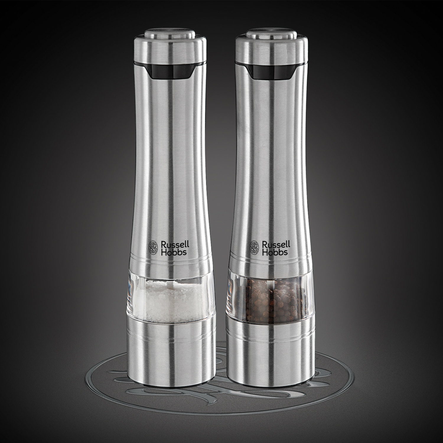 Due macinasale e pepe in acciaio inox su una superficie scura, con base trasparente.