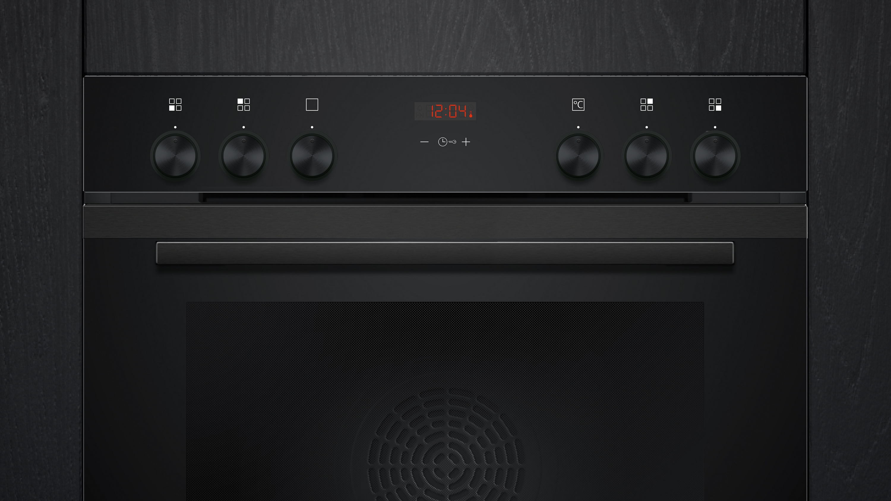 Schwarzes Backofen-Bedienfeld mit Knöpfen, Digitaluhr und Türgriff, vor dunklem Holzhintergrund.