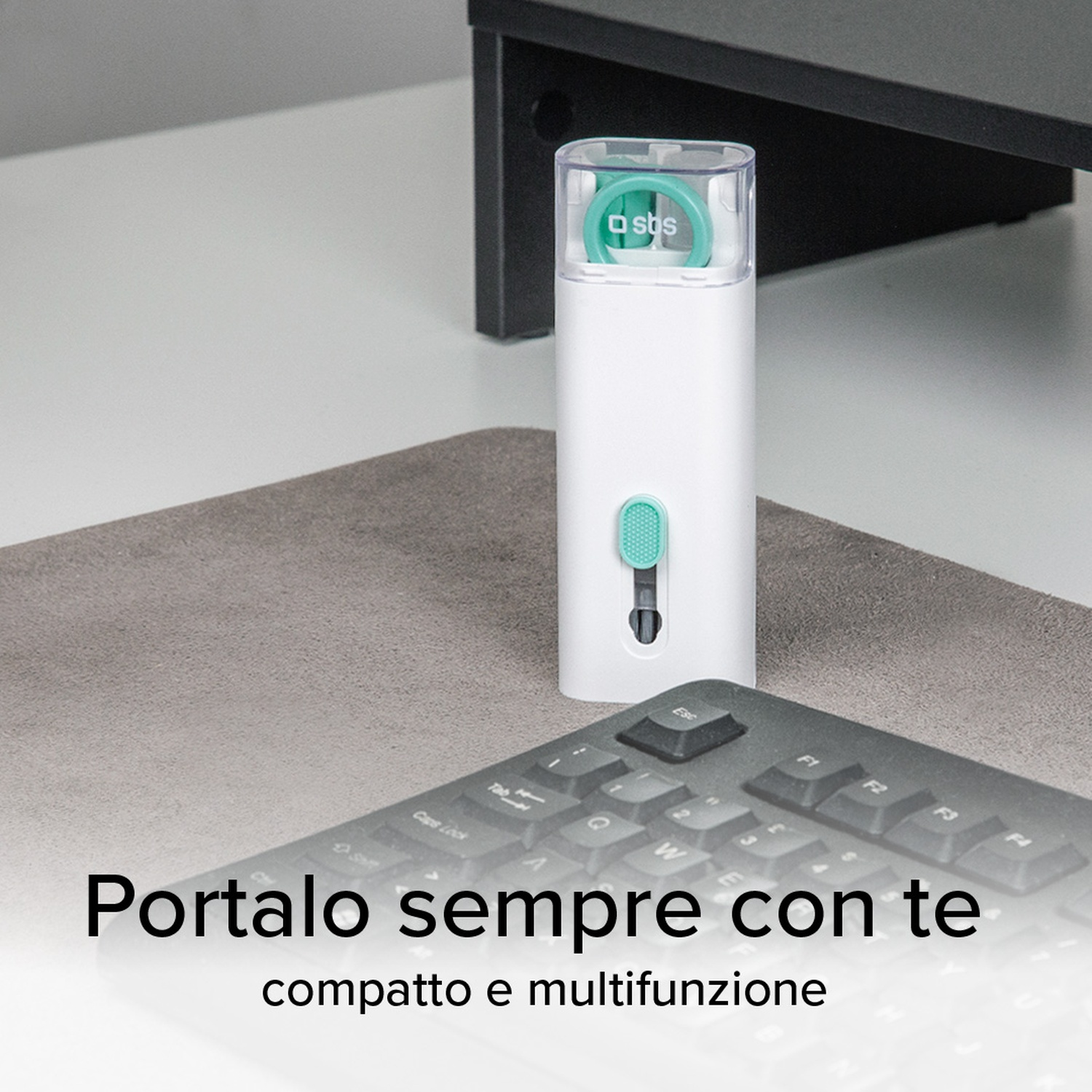 Strumento di pulizia bianco e verde acqua su una scrivania grigia. Tastiera nera sullo sfondo.