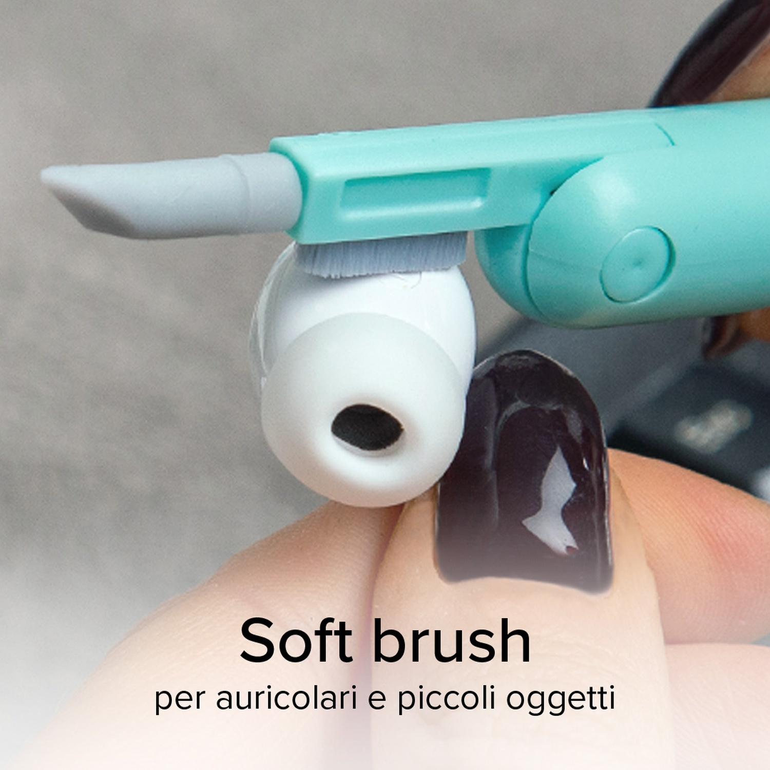 Uno strumento pulisce un auricolare bianco. Lo strumento è turchese con una spazzola grigia.