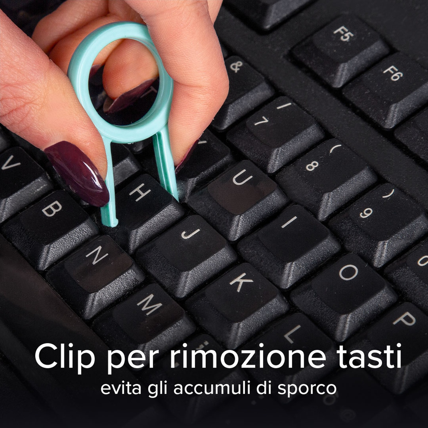 Una mano che tiene un estrattore di tasti sopra una tastiera nera. L'estrattore è verde acqua.