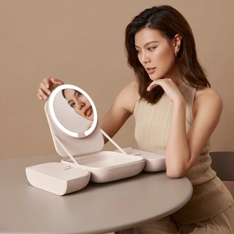 Kobieta patrząca na swoje odbicie w podświetlanym lusterku do makijażu.