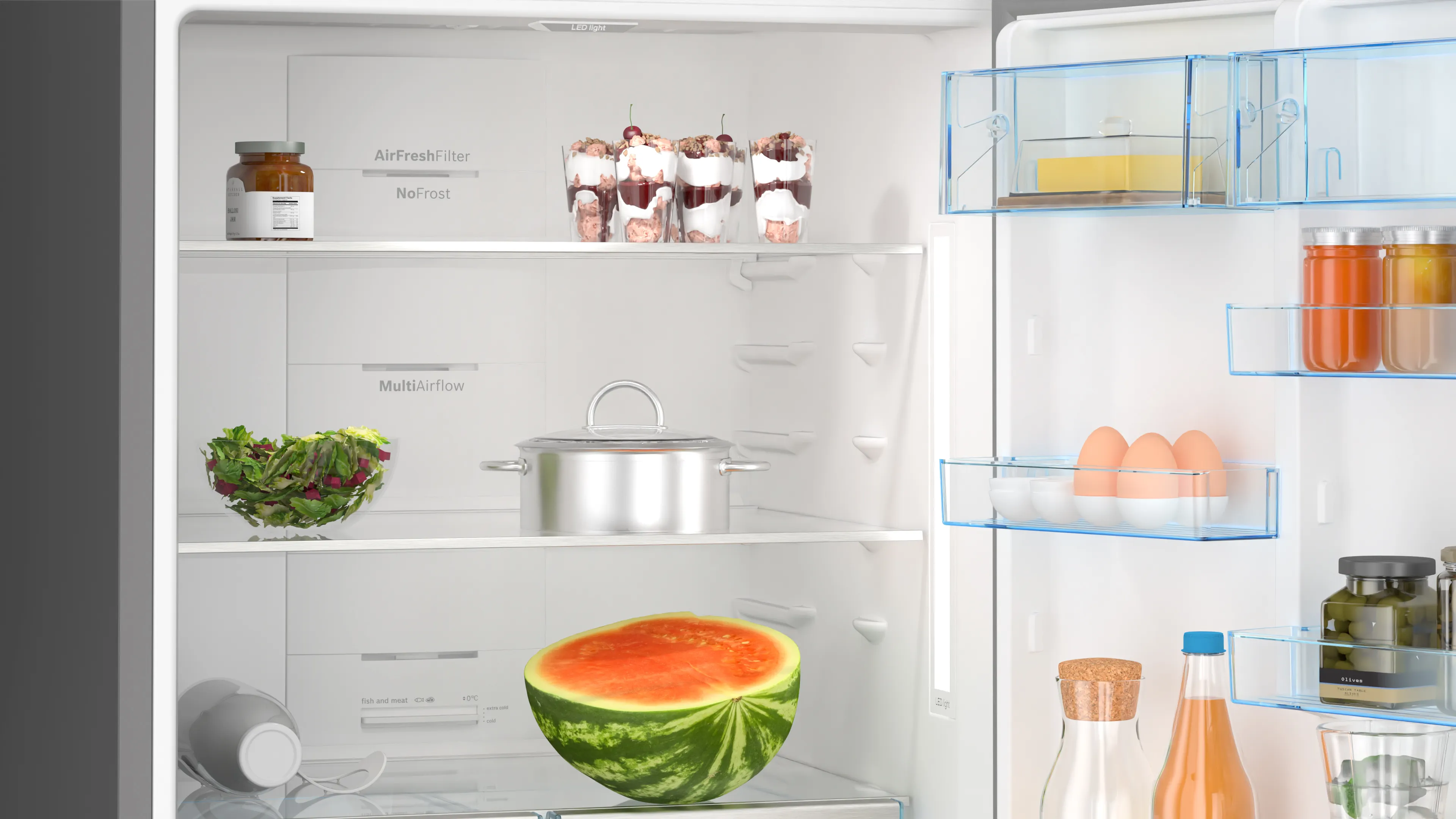 Buzdolabının içinde salata, yumurta ve karpuz gibi yiyecekler var. Buzdolabı açık.
