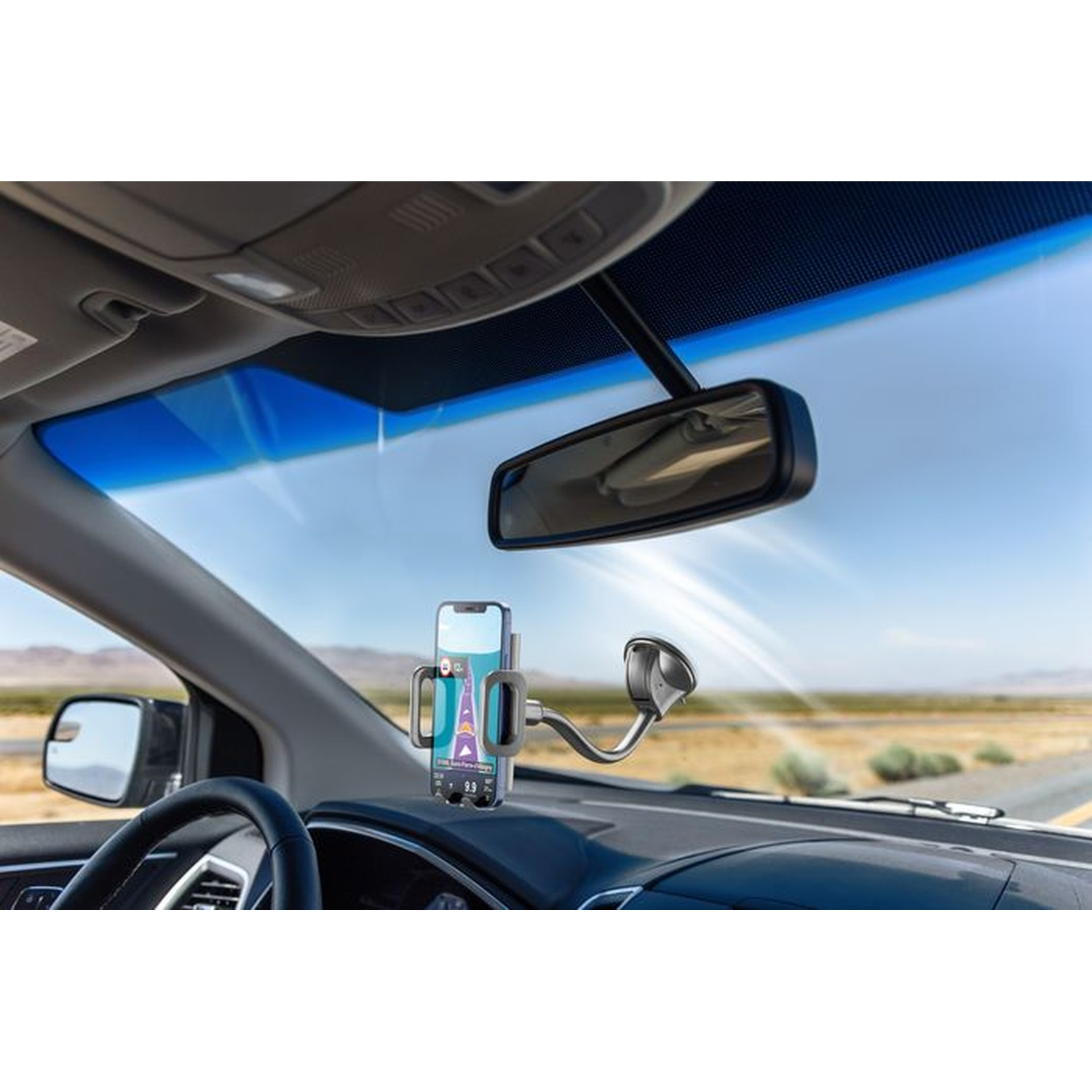 Vista interna dell'auto, telefono in un supporto sul cruscotto, specchietto retrovisore e cielo blu.