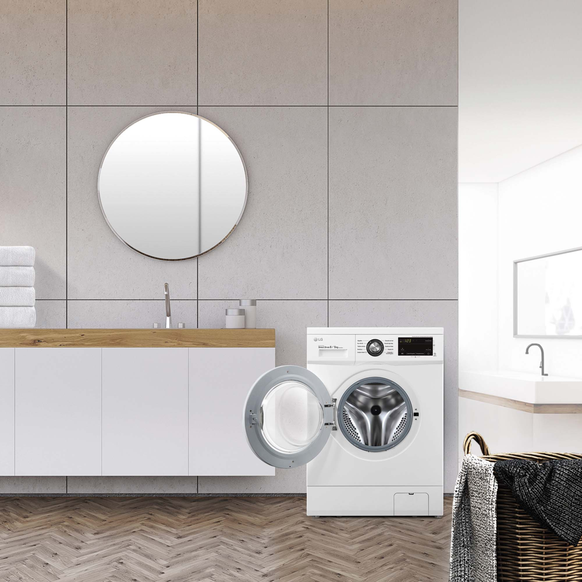 Escena de baño con lavadora blanca con puerta abierta, espejo y cesta.