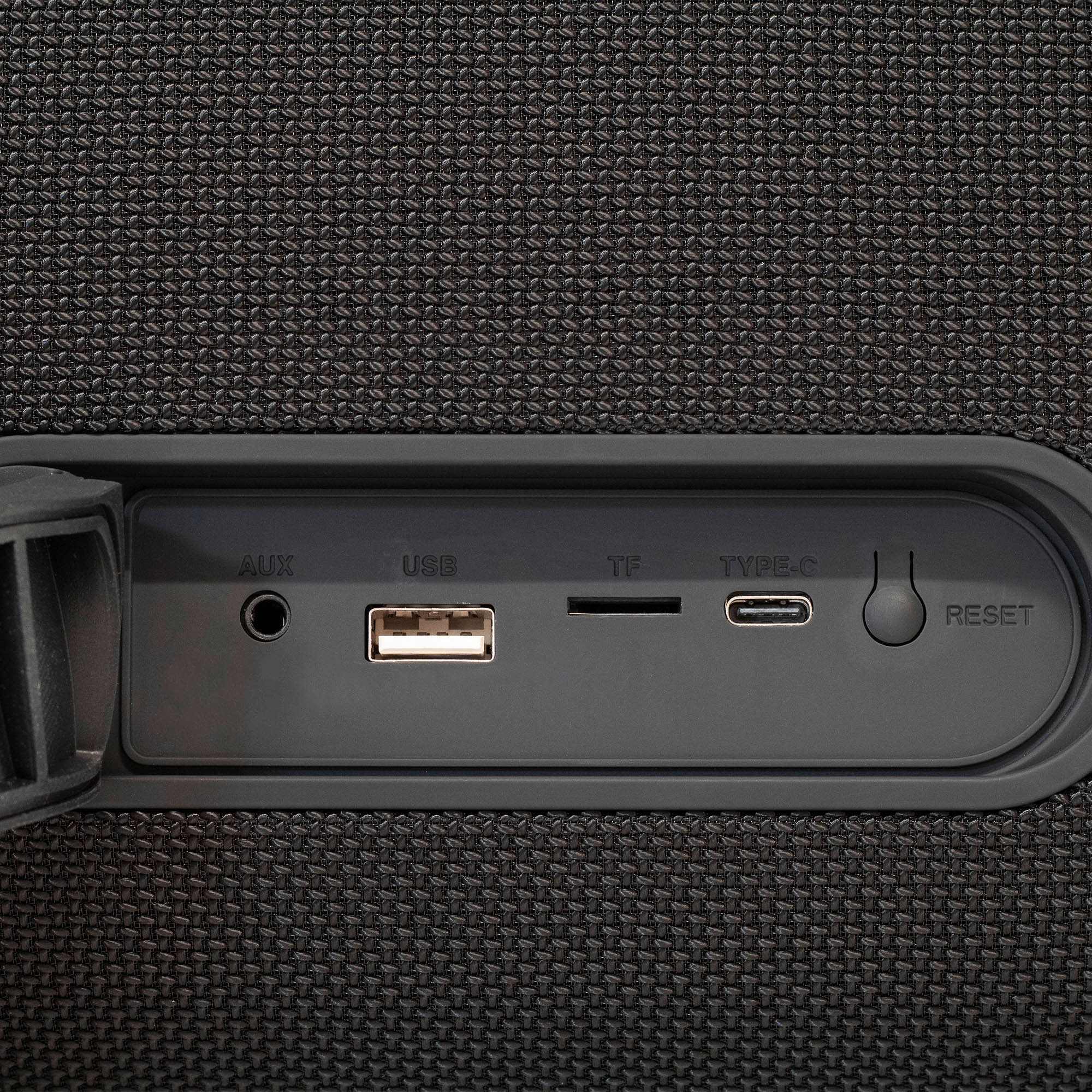 Fekete hangszóró AUX, USB, TF, Type-C és reset portokkal, texturált felületen.