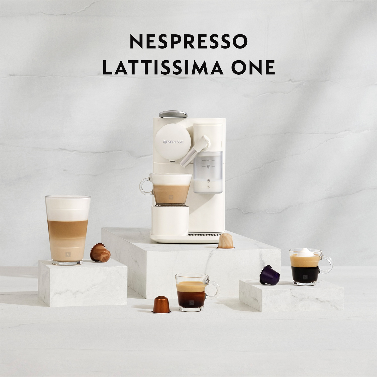 Una macchina da caffè bianca con tazze di caffè e capsule su marmo.