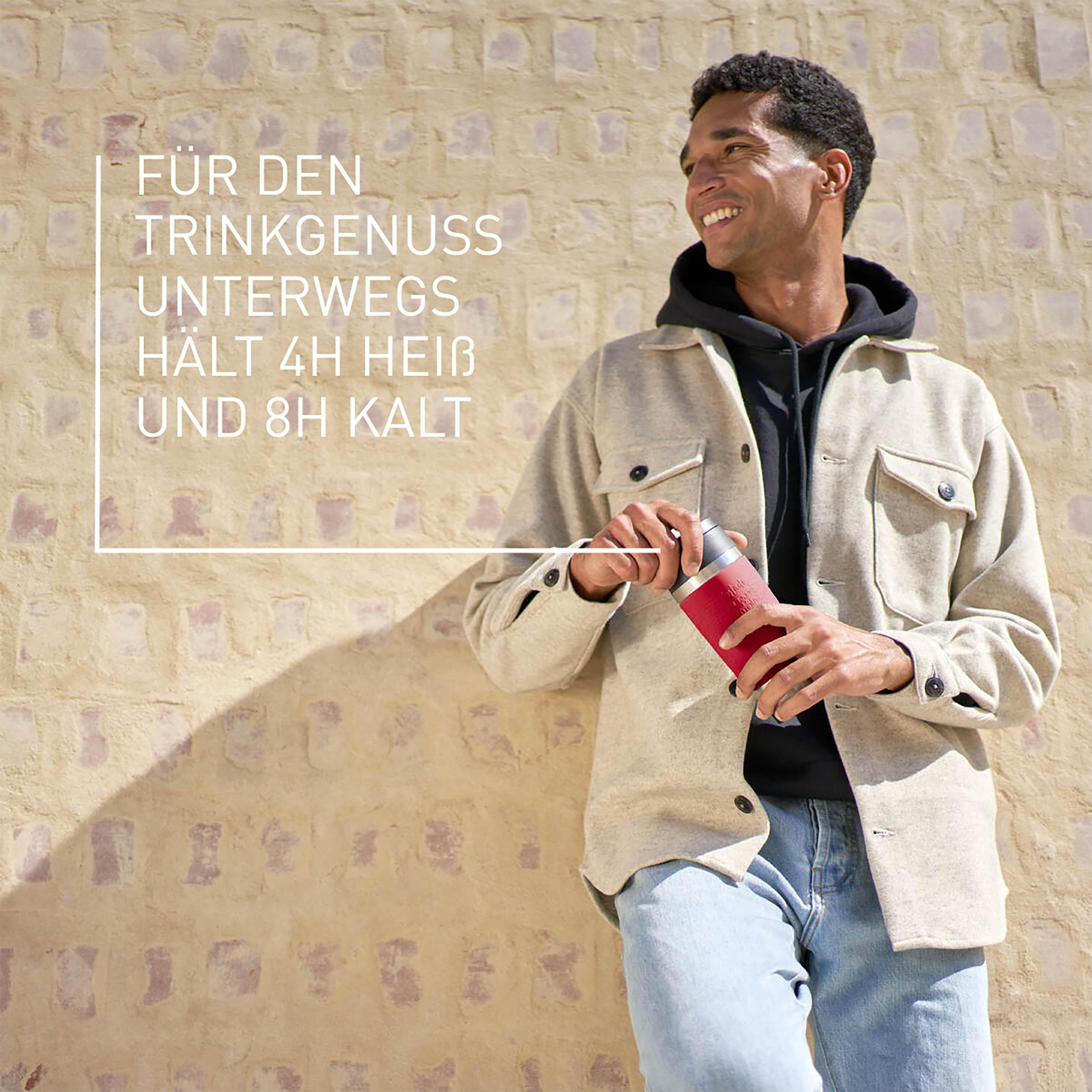 Ein lächelnder Mann hält eine rote Thermoskanne, Text überlagert auf einer strukturierten Wand.