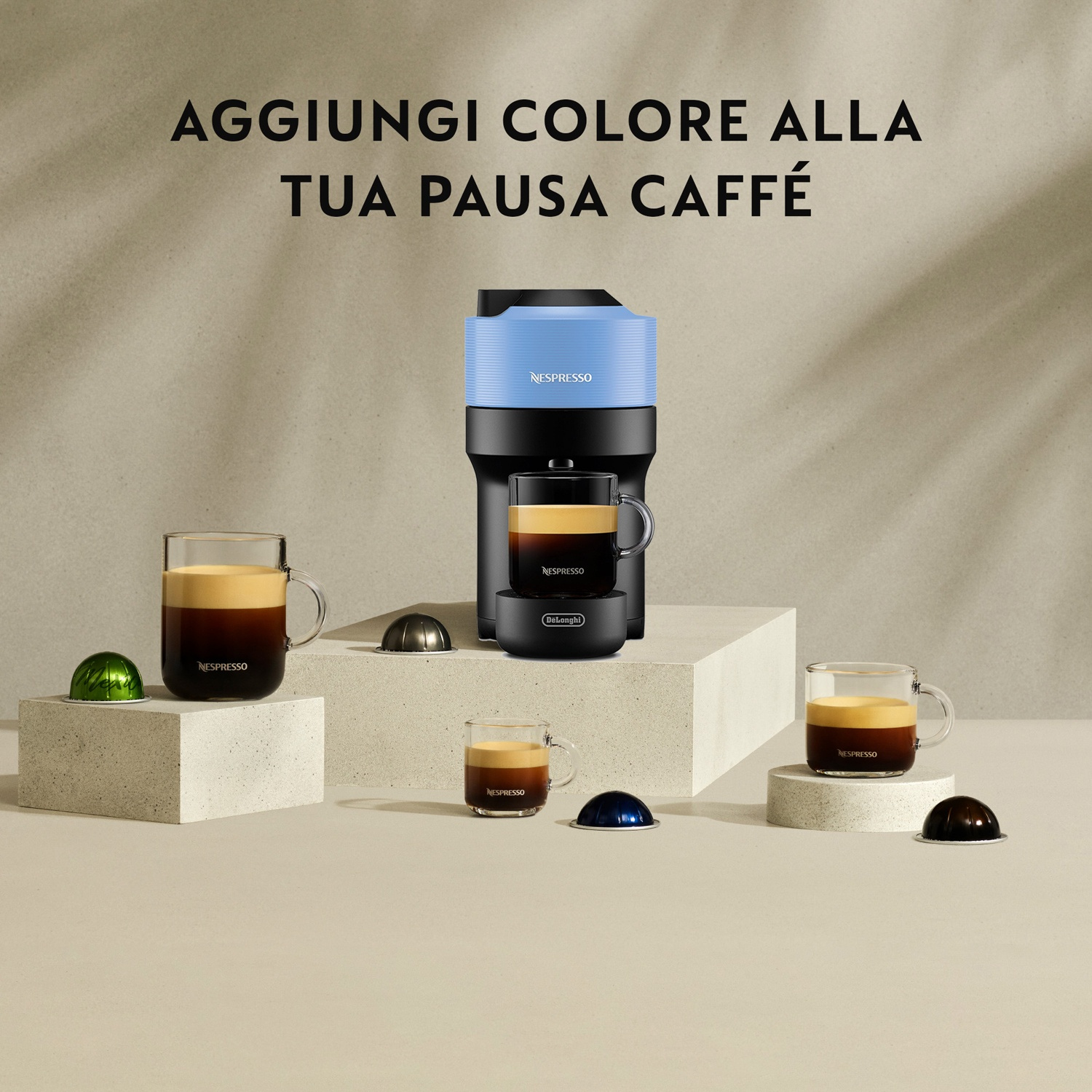 Macchina da caffè con tazze e capsule su sfondo chiaro.