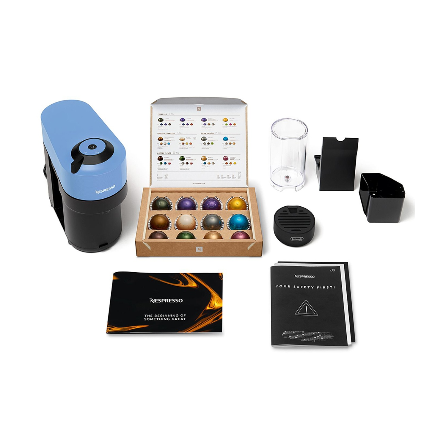 Macchina Nespresso e accessori. Macchina blu, scatola di capsule e vari altri oggetti.