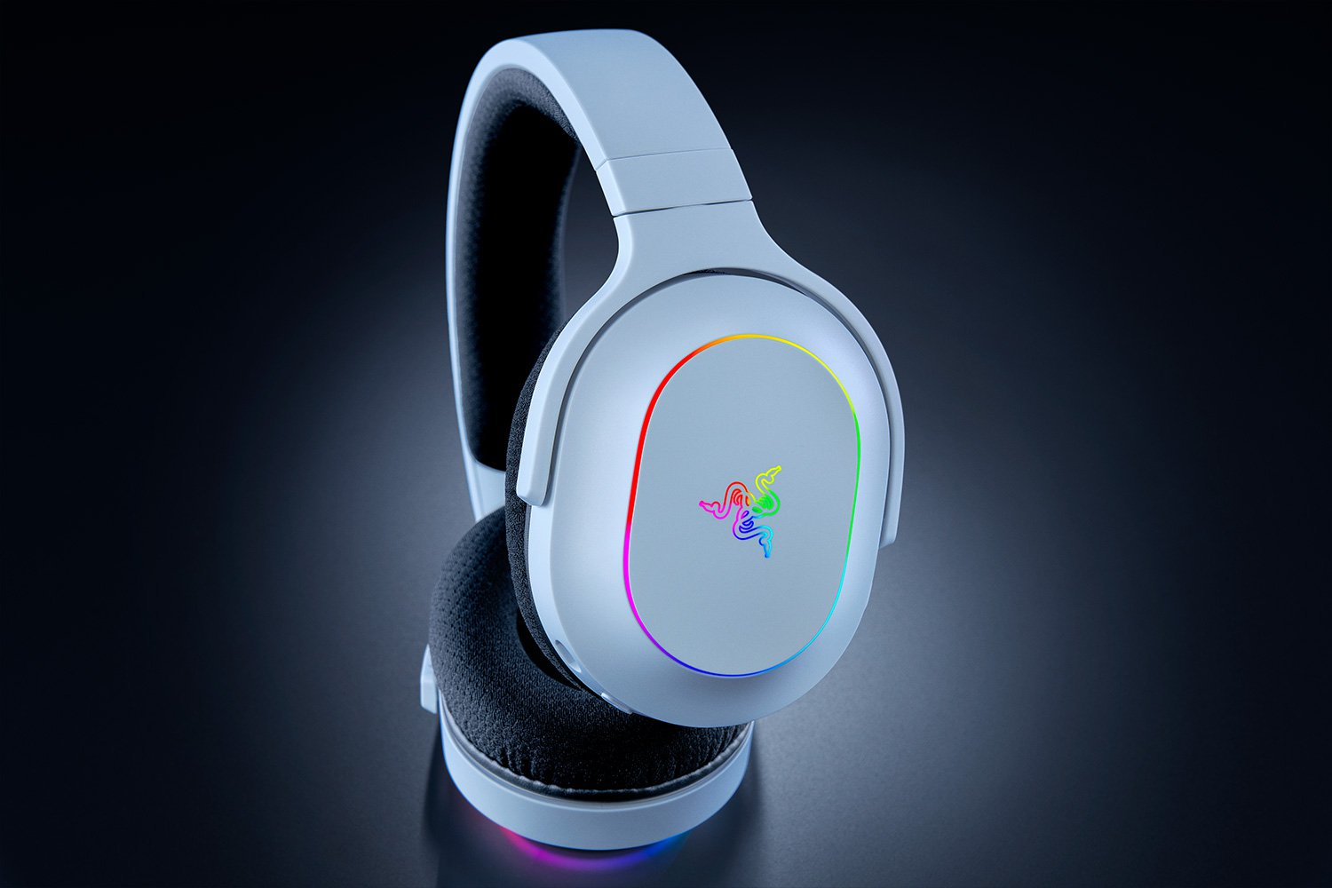 Weiße Gaming-Kopfhörer mit farbigen Lichtern und Razer-Logo auf dunkler Oberfläche.