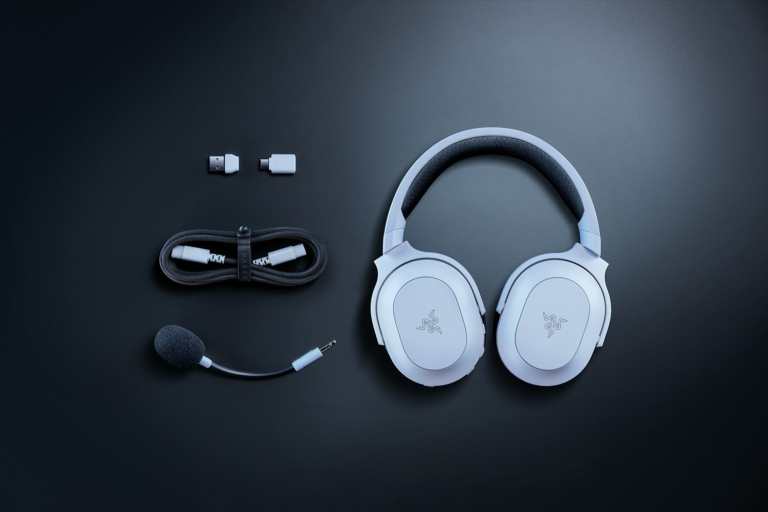 Ein Paar weißer Over-Ear-Kopfhörer mit Mikrofon und diversen Zubehörteilen.