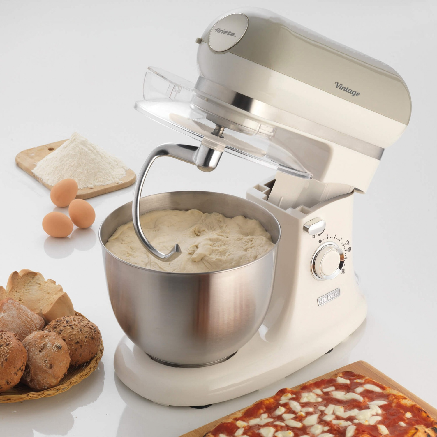Un'impastatrice Ariete color crema vintage con ingredienti e prodotti da forno intorno.